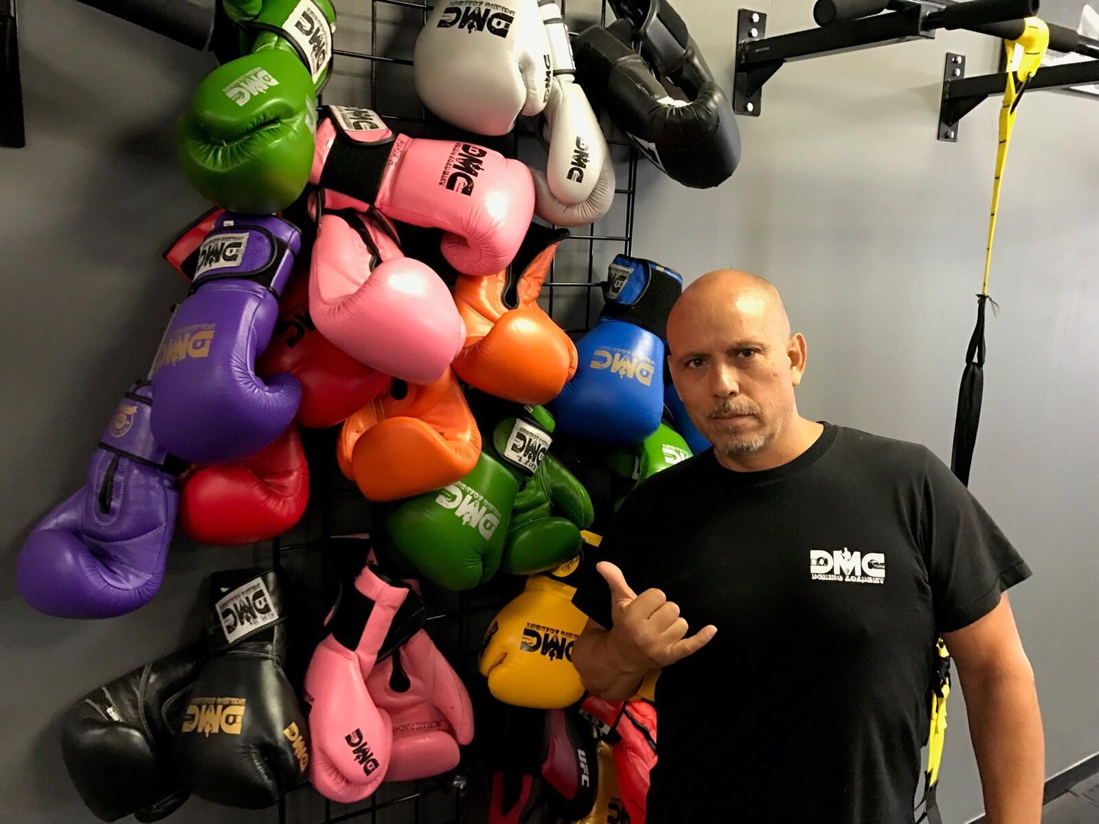 Daniel Meza-Cuadra stands next to boxing gloves hung on wall in his DMC Boxing Academy. Tom Archdeacon/CONTRIBUTED