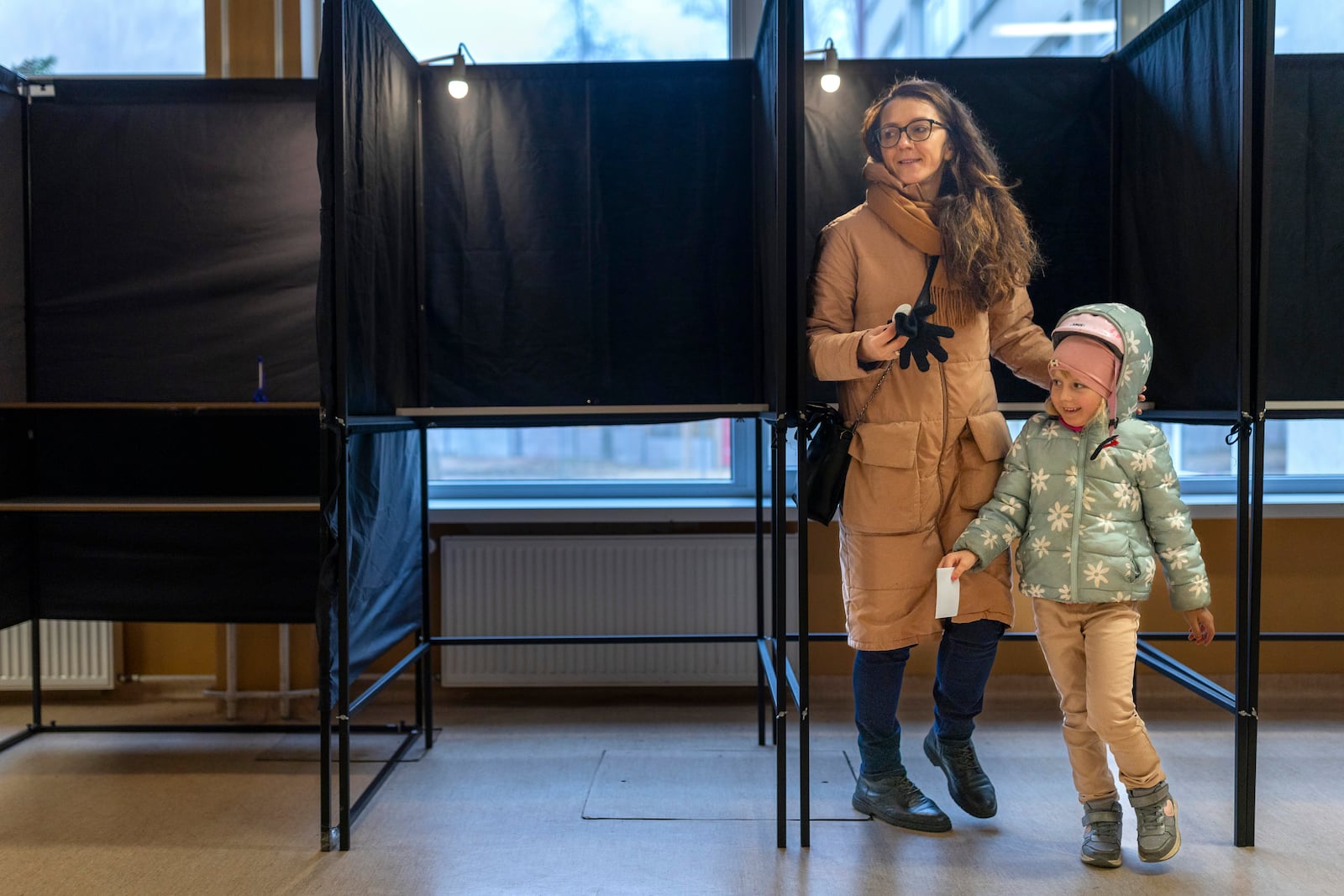 A woman with a child prepare to cast a ballot at a polling station during a second round of voting in parliamentary election, in Vilnius, Lithuania, Sunday, Oct. 27, 2024. (AP Photo/Mindaugas Kulbis)