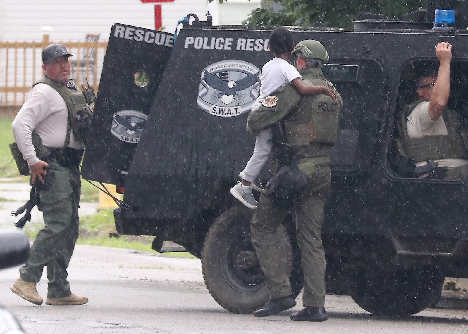 A police officer carries a young boy to an armored vehicle Monday, June 6, 2022 after he was removed from a house along South Lowry Avenue where a stand-off had been going on for several hours. BILL LACKEY/STAFF