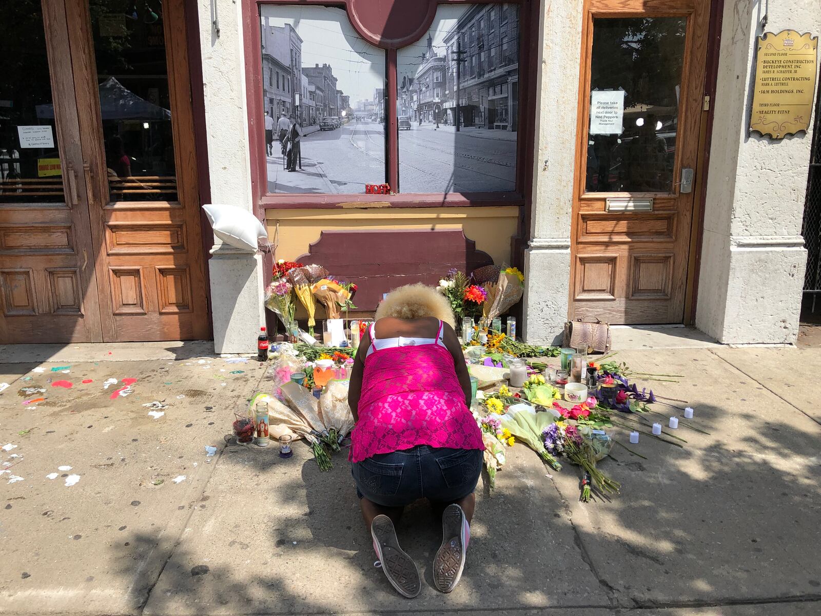 Annette Gibson-Strong cries in front of the memorial to the victims of the Oregon District mass shooting on Monday. She painstakingly moved the memorial so that Ned Peppers Bar could open that day. BONNIE MEIBERS/STAFF