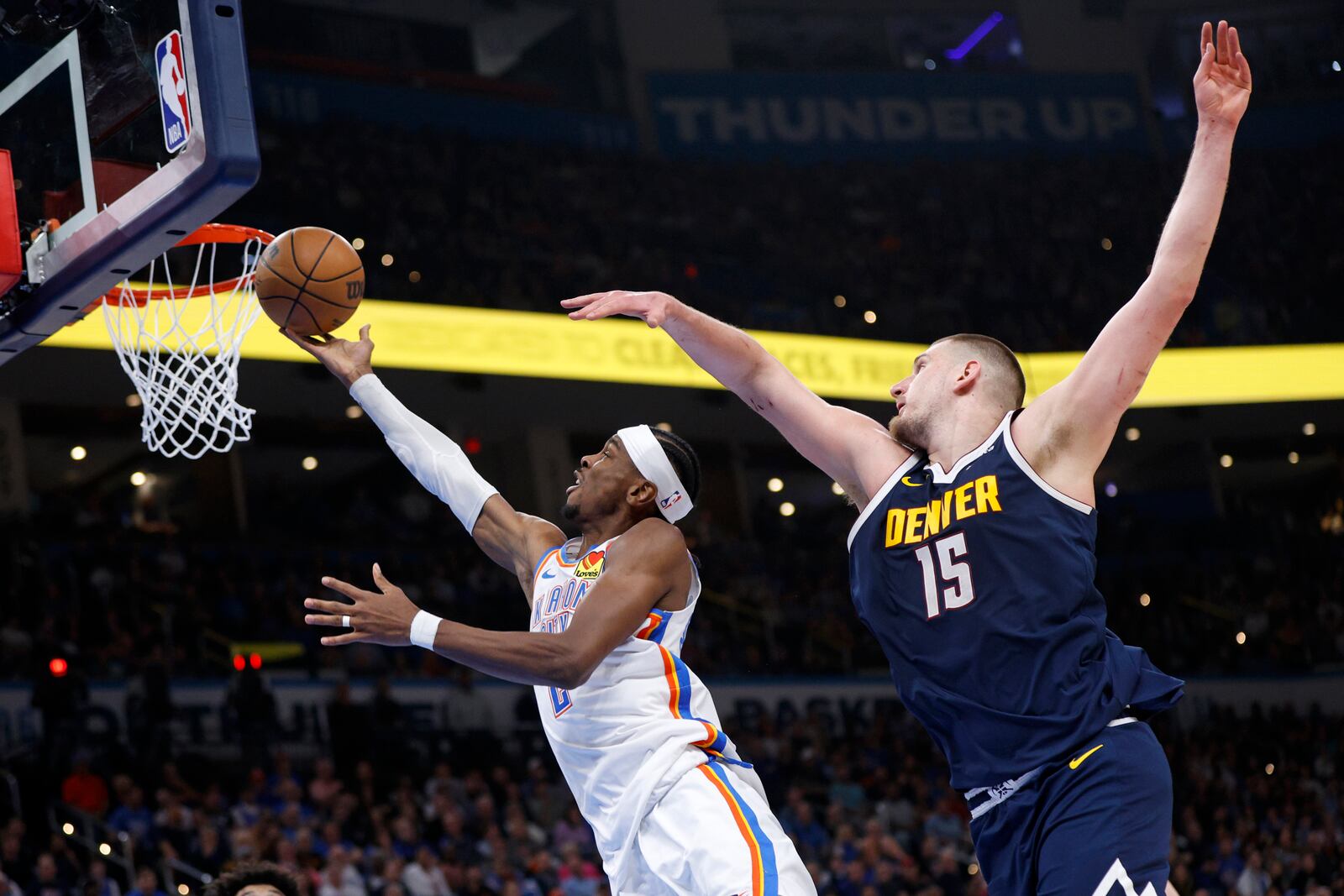 Oklahoma City Thunder guard Shai Gilgeous-Alexander, left, takes the ball to the basket in front of Denver Nuggets center Nikola Jokic (15) during the first half of an NBA basketball game Monday, March 10, 2025, in Oklahoma City. (AP Photo/Nate Billings)