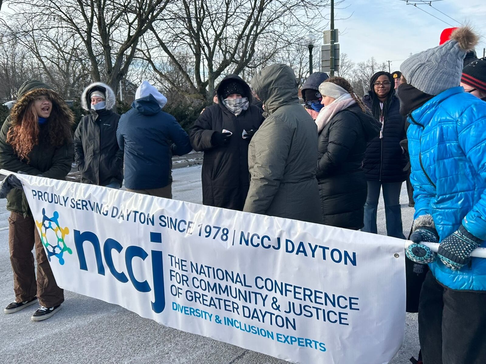 Members of the National Conference For Community and Justice of Greater Dayton on Monday hold a banner as they walk in the Dayton MLK March on Third Street. Eileen McClory/Staff Photo