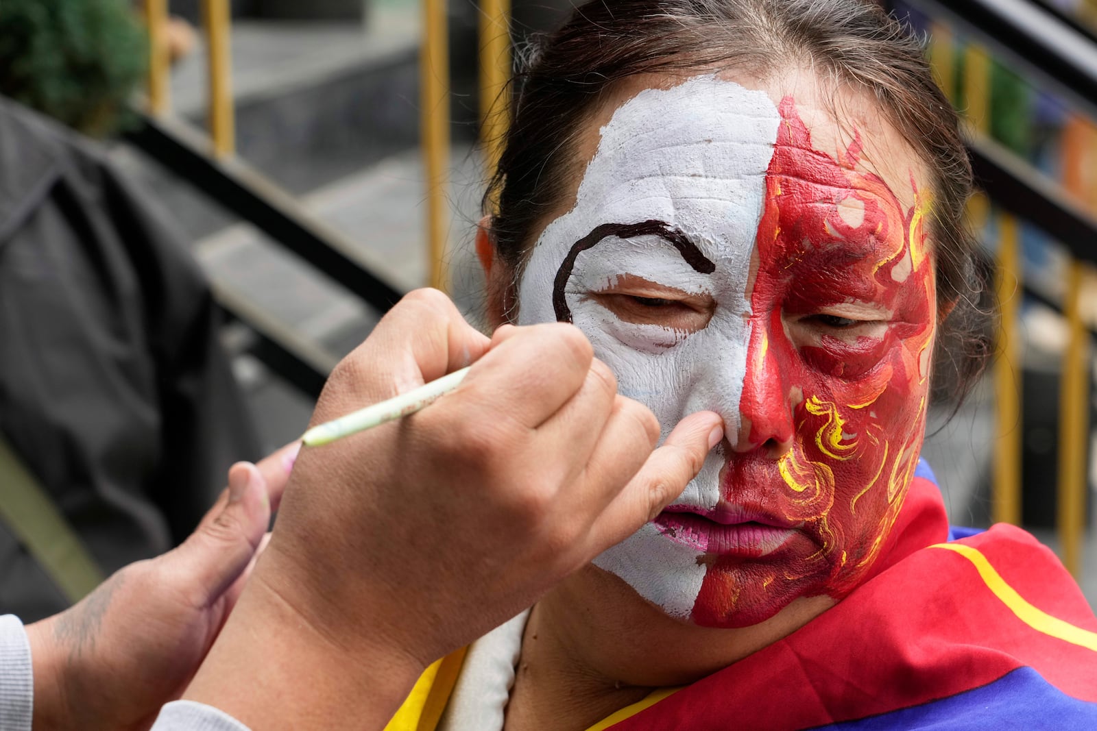 An exiled Tibetan gets her face painted before participating in a march to mark the 66th anniversary of an uprising in Tibetan capital Lhasa, as they gather at the Tsuglakhang temple in Dharamshala, India, Monday, March 10, 2025. (AP Photo/Ashwini Bhatia)