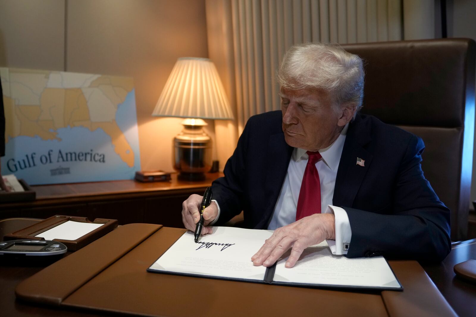 President Donald Trump signs a proclamation declaring Feb. 9 Gulf of America Day, aboard Air Force One as he travels from West Palm Beach, Fla. to New Orleans, Sunday, Feb. 9, 2025. (AP Photo/Ben Curtis)