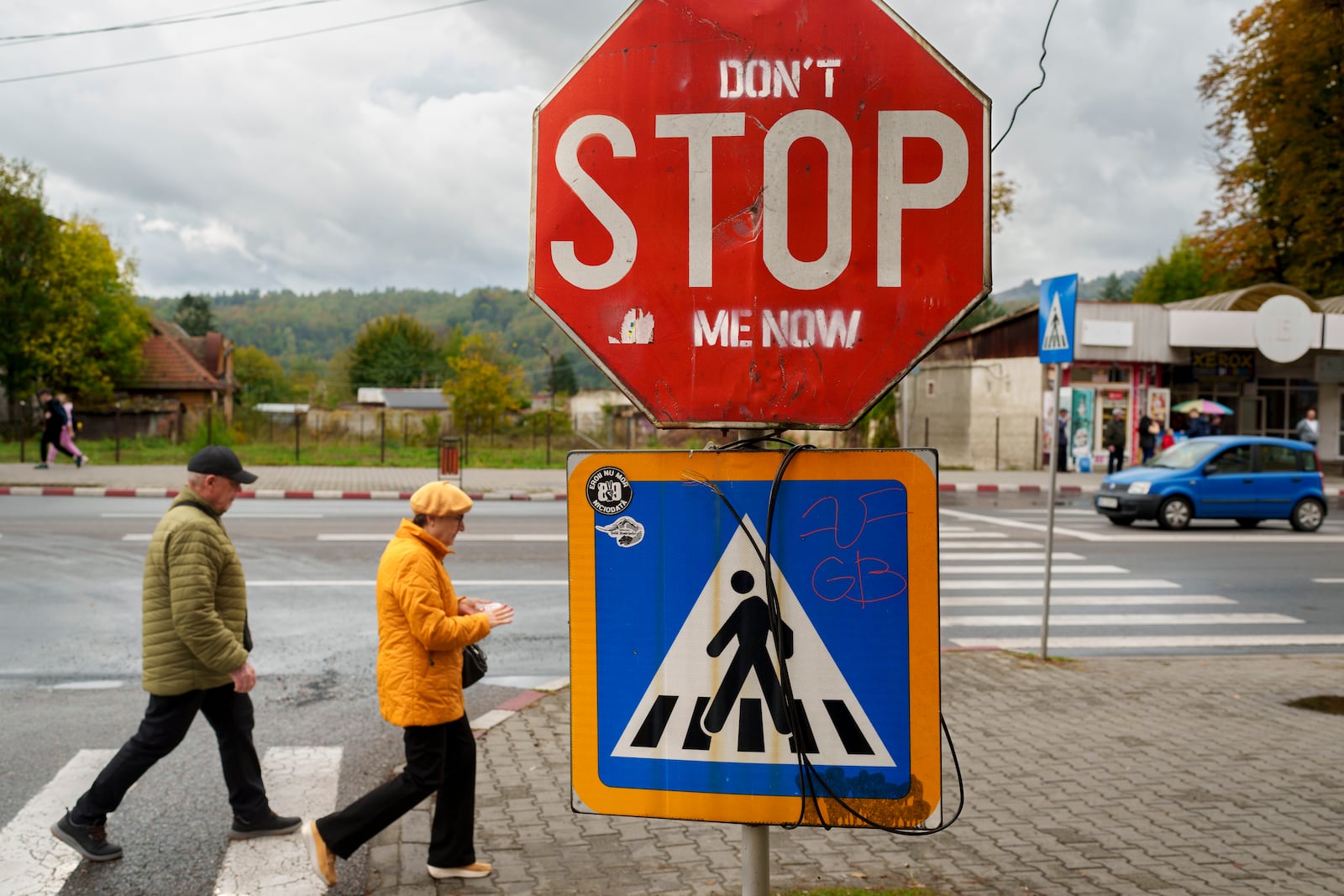 People cross a street in Petrosani, southern Romania, Friday, Oct. 11, 2024. (AP Photo/Vadim Ghirda)