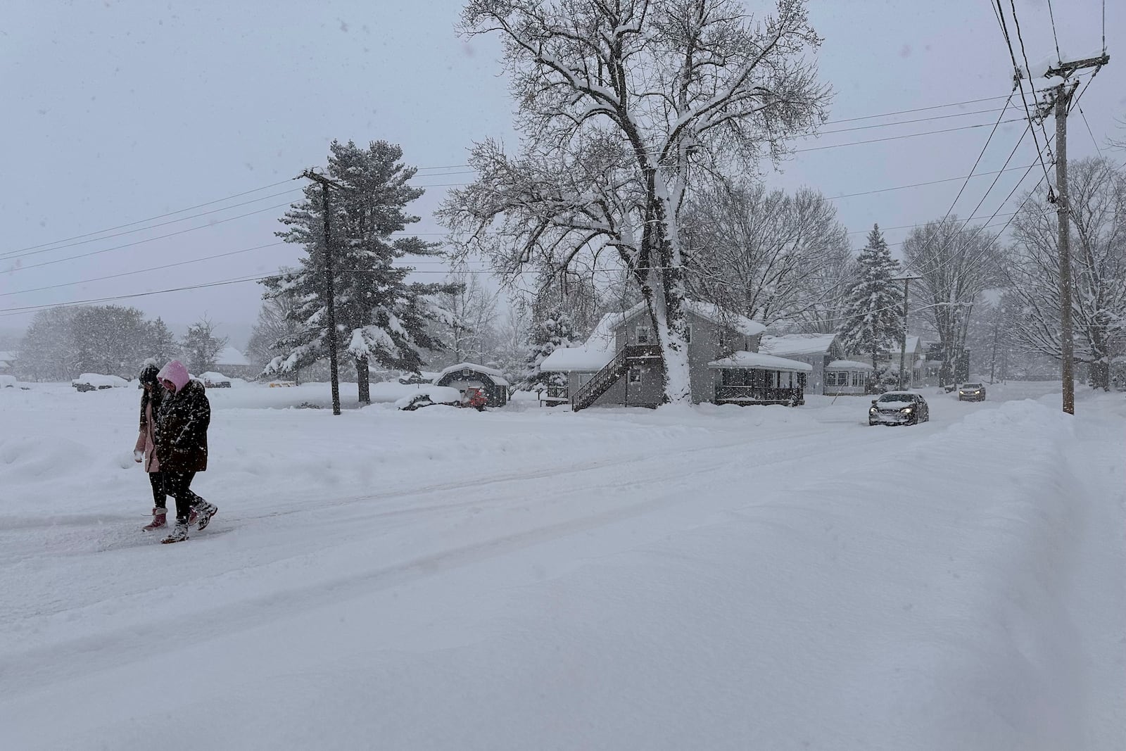 People walk in lake-effect snow on Sunday, Dec. 1, 2024, in Lowville, N.Y. (AP Photo/Cara Anna)