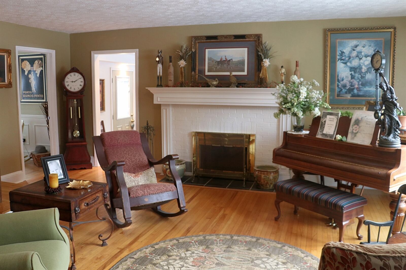 Formal entry opens from the covered front door directly into the living room, which has refinished hardwood flooring, a semi-open staircase with spindled accents and a wood-burning fireplace with a painted wood mantel and brick surround. 