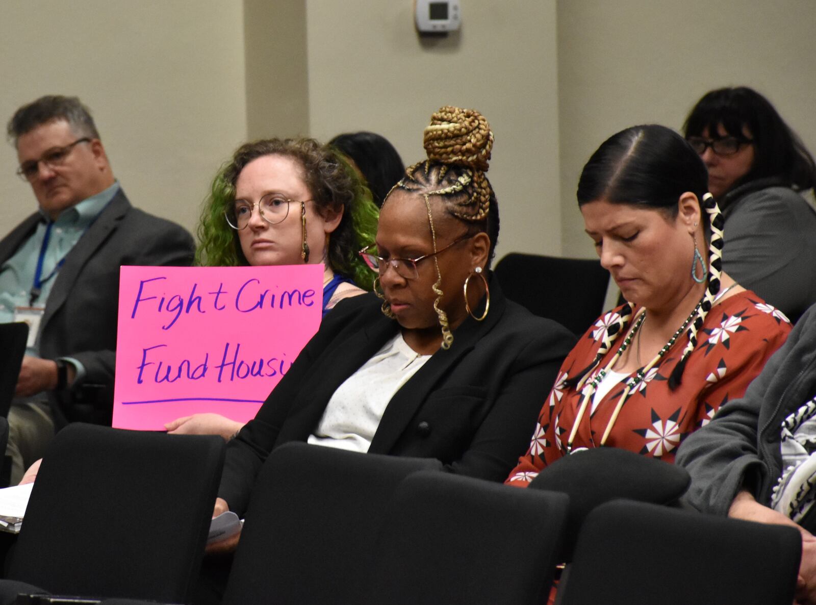 Viridis Green, a member of the Dayton Tenant Union, holds a sign while seated in the audience at a Dayton City Commission meeting. CORNELIUS FROLIK / STAFF