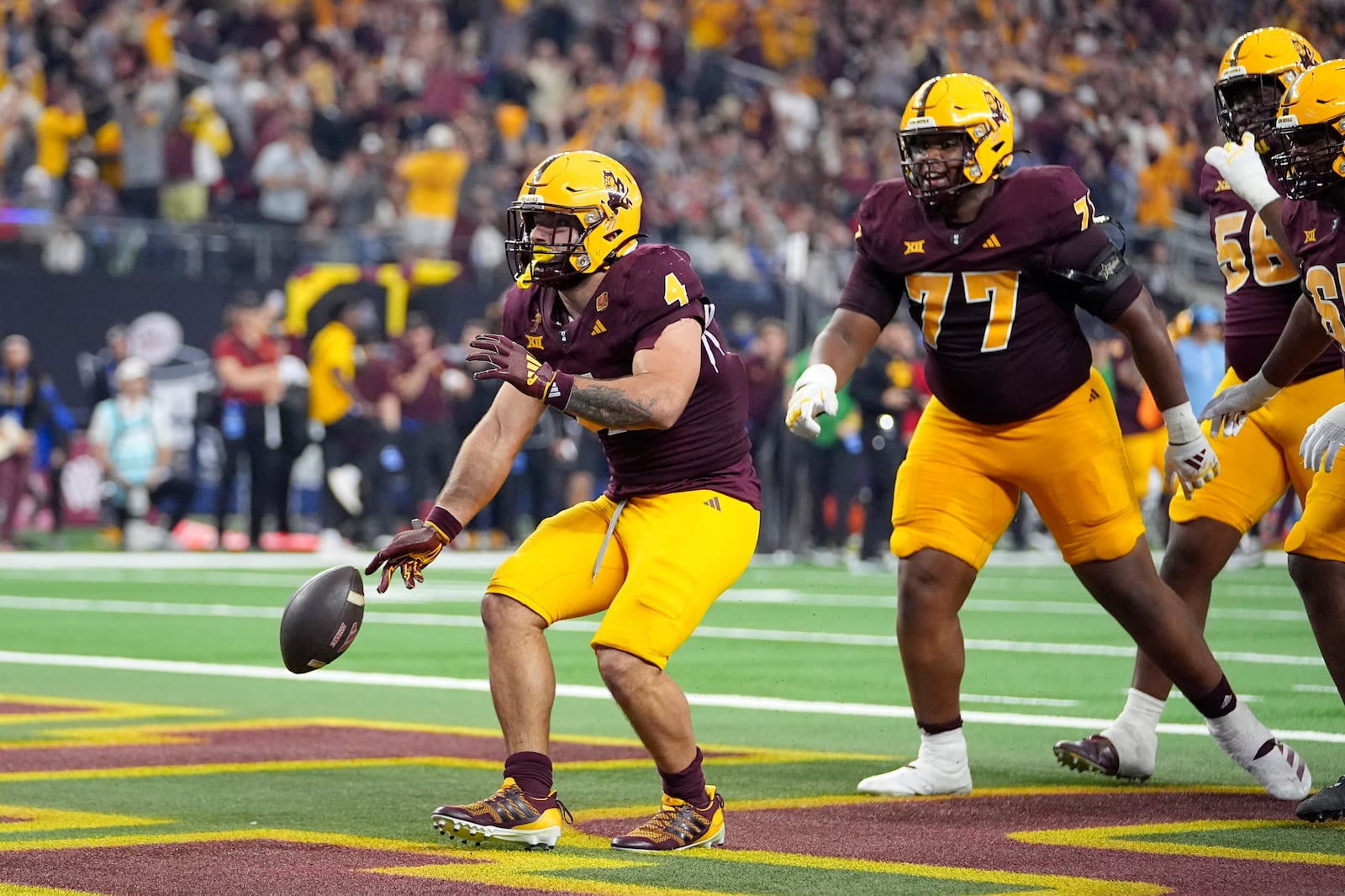 Arizona State running back Cam Skattebo (4) celebrates his touchdown run as offensive lineman Kyle Scott (77) and others look on in the first half of the Big 12 Conference championship NCAA college football game against Iowa State, in Arlington, Texas, Saturday Dec. 7, 2024. (AP Photo/Julio Cortez)