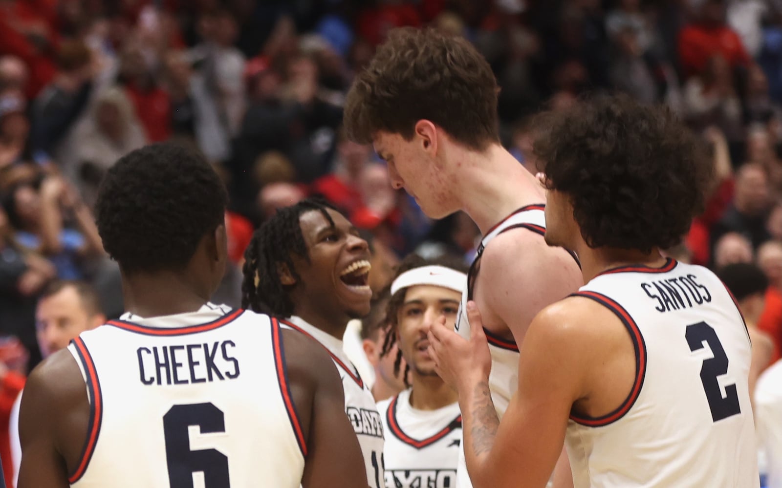 Dayton's Malachi Smith, back center, reacts to the game-winning shot by Amaël L'Etang, back right, in overtime against Loyola Chicago on Saturday, Jan. 18, 2025, at UD Arena. David Jablonski/Staff