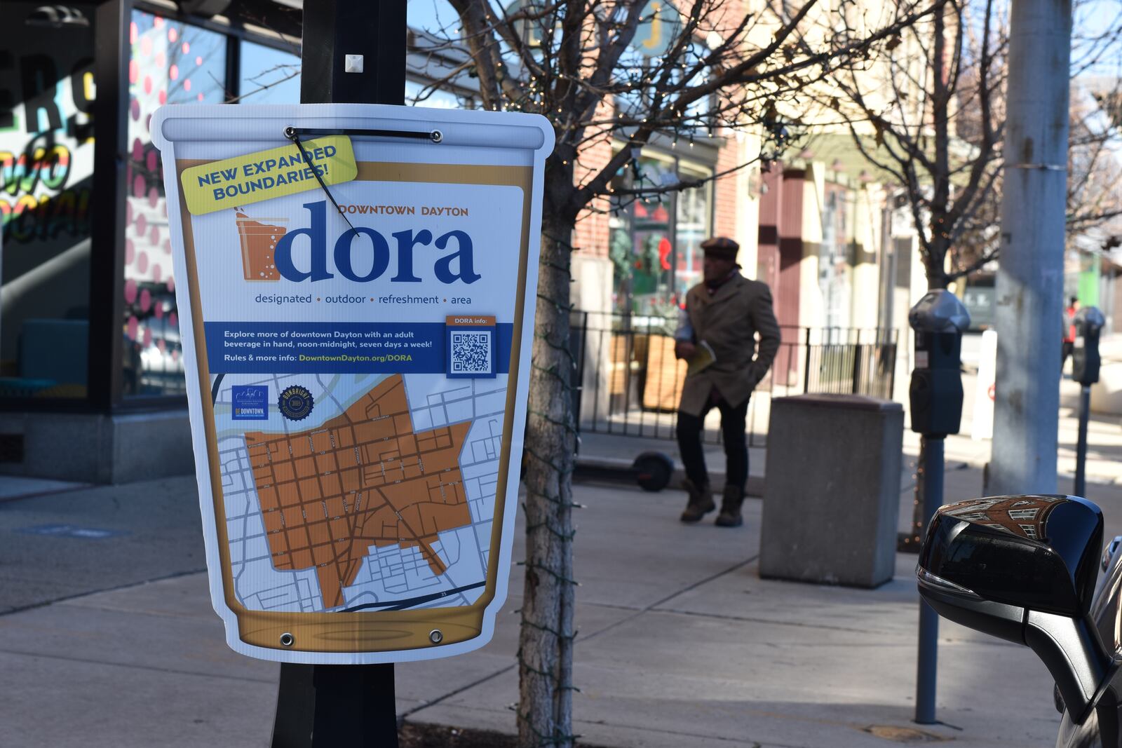 A sign in the Fire Blocks District on the 100 block of East Third Street advertising the downtown Dayton Designated Outdoor Refreshment Area (DORA). Most of downtown is inside of the DORA, which allows people to buy alcohol in special to-go cups that they can consume on the street. CORNELIUS FROLIK / STAFF