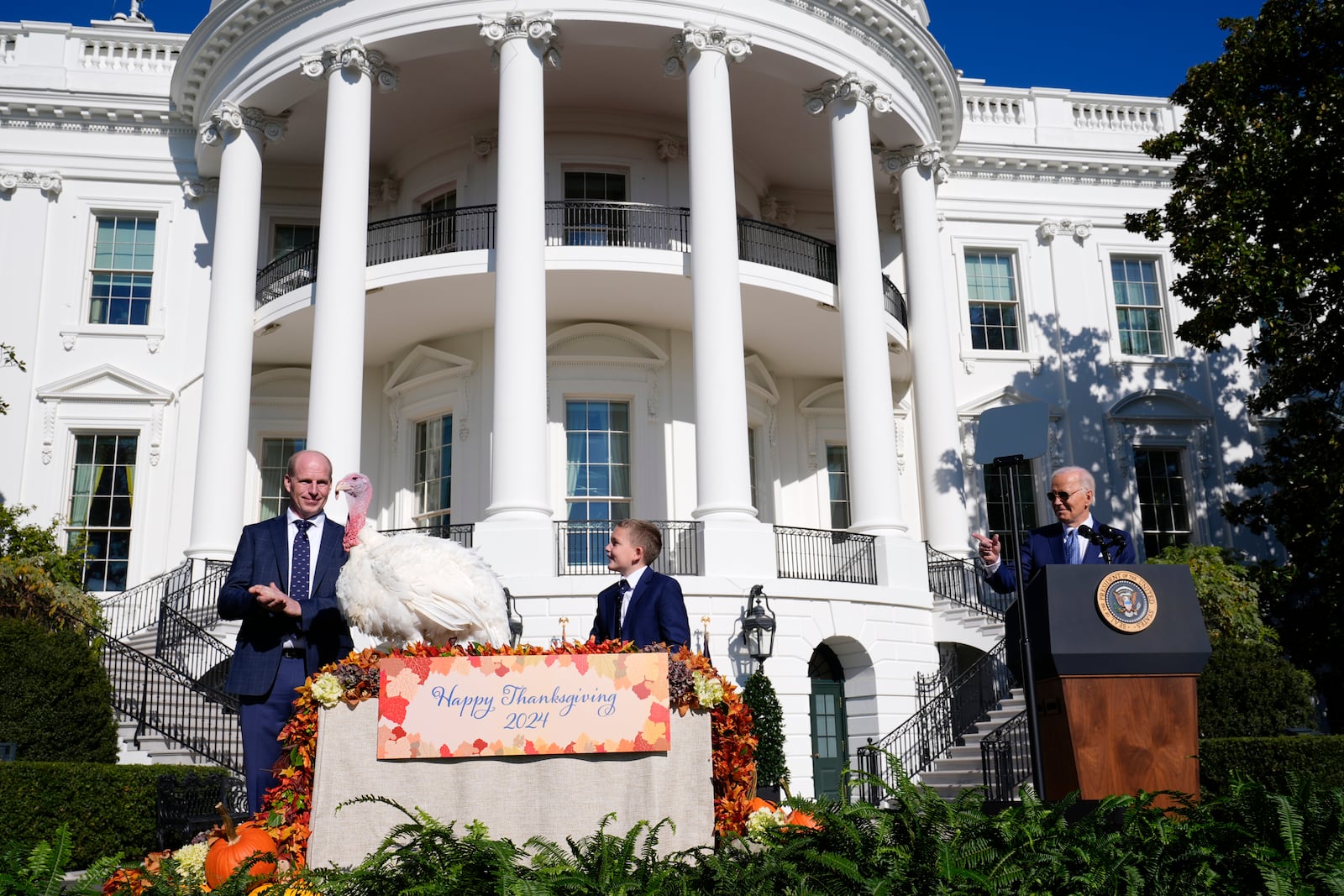 President Joe Biden speaks and pardons the national Thanksgiving turkey, Peach, during a pardoning ceremony on the South Lawn of the White House in Washington, Monday, Nov. 25, 2024, as John Zimmerman, chair of the National Turkey Federation and his son Grant, look on. (AP Photo/Susan Walsh)