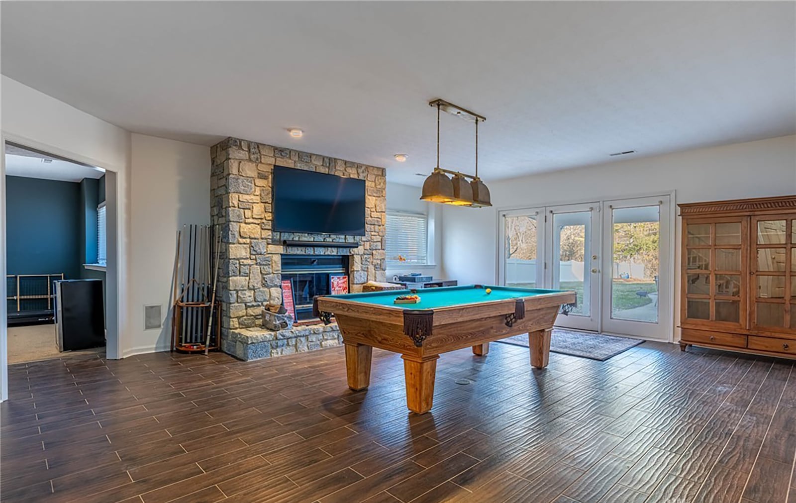 The finished walk out basement features a recreation room with stone floor to ceiling gas fireplace. It walks out to a covered patio and the pool area.