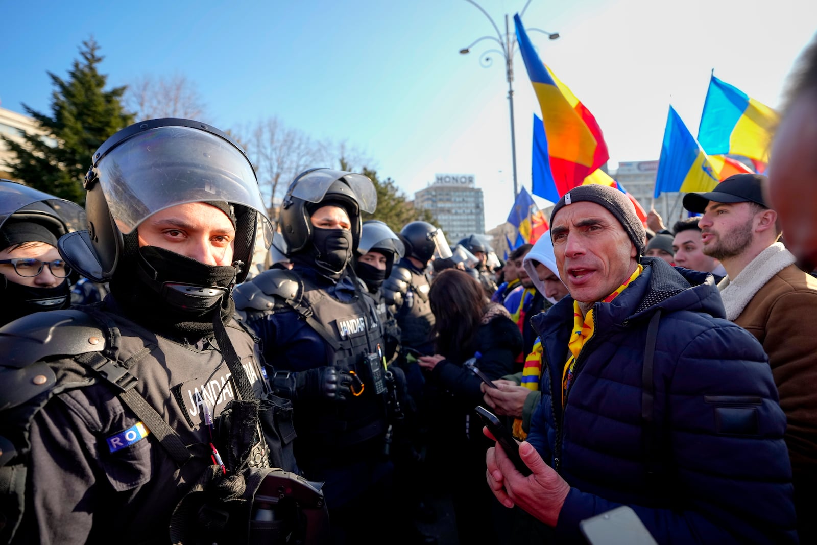 Riot police talk to supporters after scuffling during a protest by supporters of Calin Georgescu, the winner of Romania's first round of presidential election which the Constitutional Court later annulled in Bucharest, Romania, Monday, Feb. 10, 2025. (AP Photo/Vadim Ghirda)