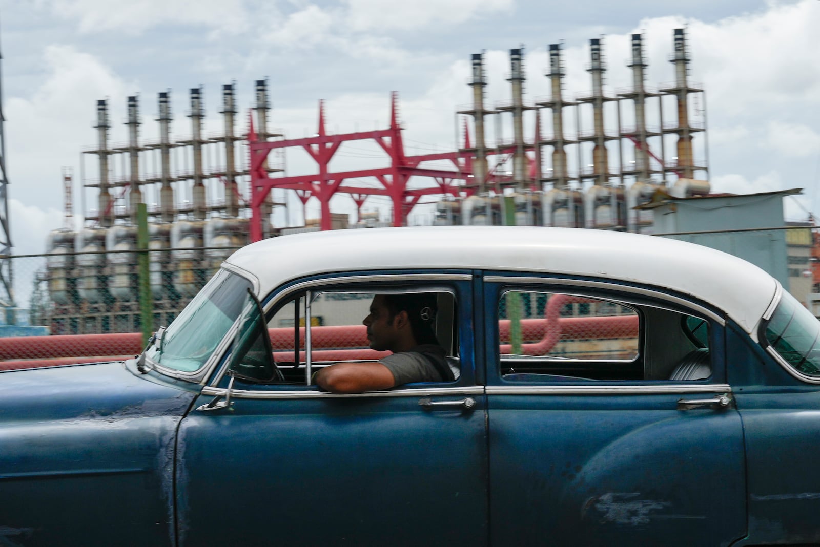 A person drives a classic American car past a floating generator that has not been producing electricity for days in Havana, Cuba, Friday, Oct. 18, 2024. (AP Photo/Ramon Espinosa)