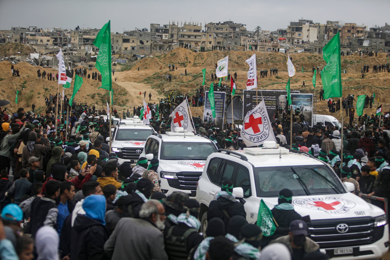 Palestinians gather as Hamas fighters escort Red Cross vehicles carrying coffins containing the bodies of four Israeli hostages, including a mother and her two children, who had long been feared dead, to the Red Cross in Khan Younis, southern Gaza Strip, Thursday, Feb. 20, 2025. (AP Photo/Jehad Alshrafi)