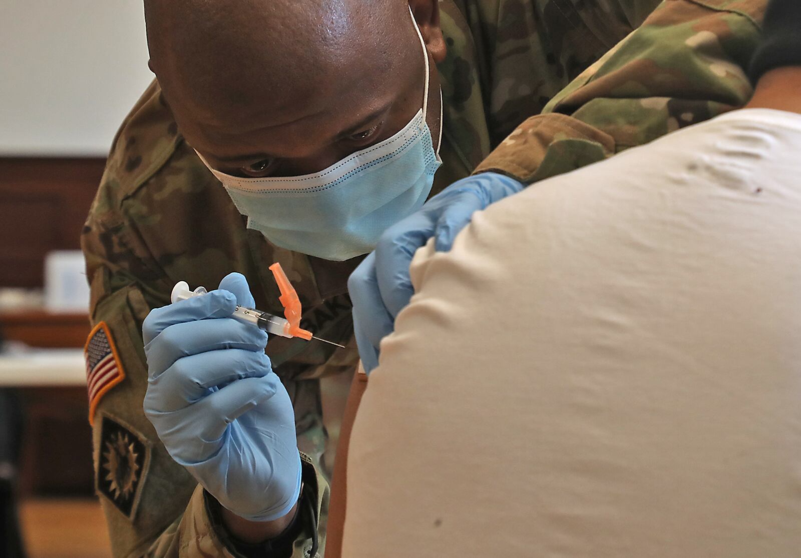 Army National Guard Sgt. Ricky Baker assists with giving COVID-19 vaccines earlier this year. BILL LACKEY/STAFF