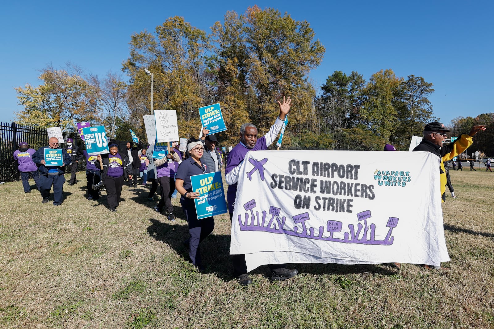 Airport workers wave signs as they march in front of the Charlotte Douglas International Airport in Charlotte, N.C., Monday, Nov. 25, 2024. (AP Photo/Nell Redmond)