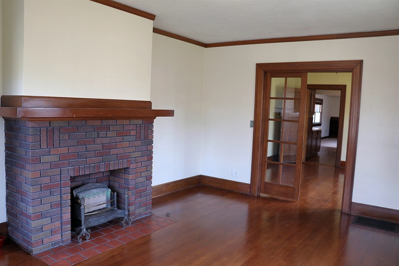 A brick fireplace has a built-in design. There is a terra cotta tile hearth and a wooden mantel.