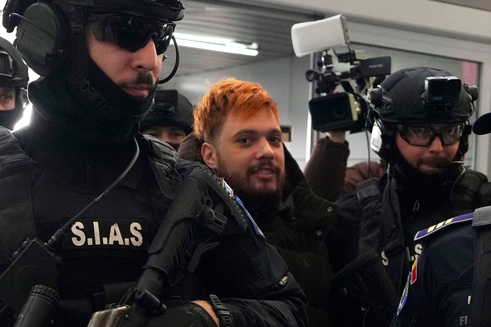 Mohamed Amra, nicknamed ''The Fly", is escorted by armed police officers at the Henri Coanda international airport in Otopeni, Romania, Tuesday, Feb. 25, 2025, before being extradited to France. (AP Photo/Vadim Ghirda)