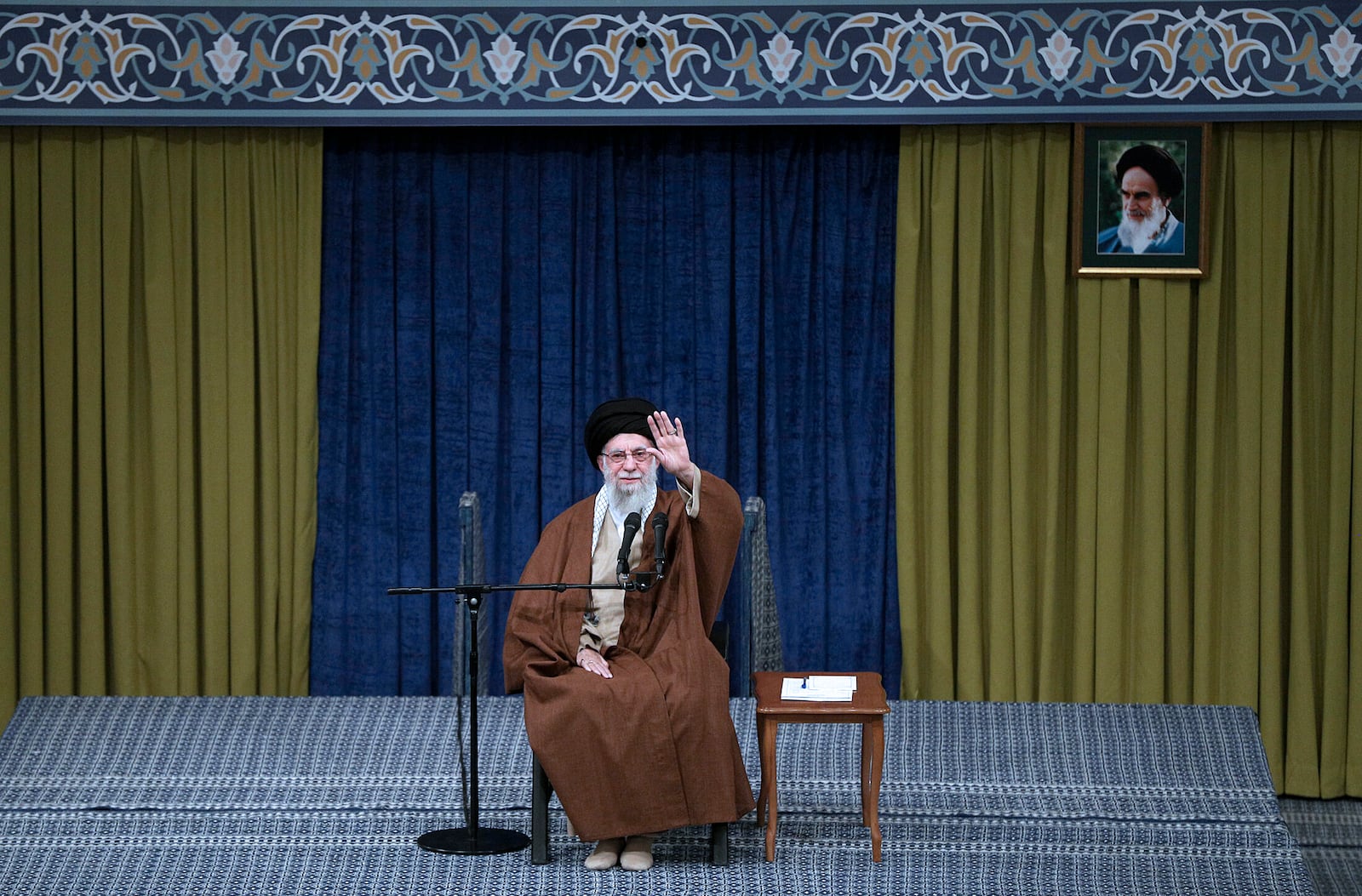 In this photo released by the official website of the office of the Iranian supreme leader, Supreme Leader Ayatollah Ali Khamenei waves to the crowd during a meeting in Tehran, Iran, Sunday, Dec. 22, 2024. A portrait of the late revolutionary founder Ayatollah Khomeini hangs at right. (Office of the Iranian Supreme Leader via AP)