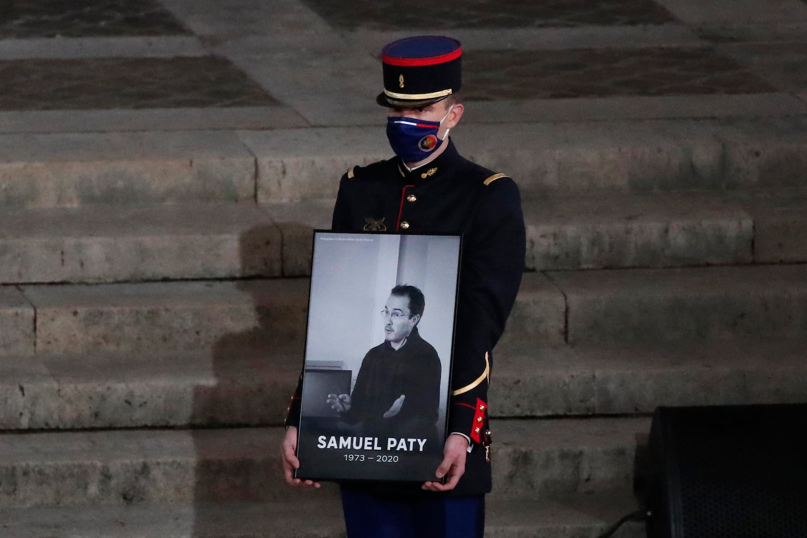 FILE - A Republican Guard holds a portrait of Samuel Paty in the courtyard of the Sorbonne university during a national memorial event, Wednesday, Oct. 21, 2020 in Paris. (AP Photo/Francois Mori, Pool, File)