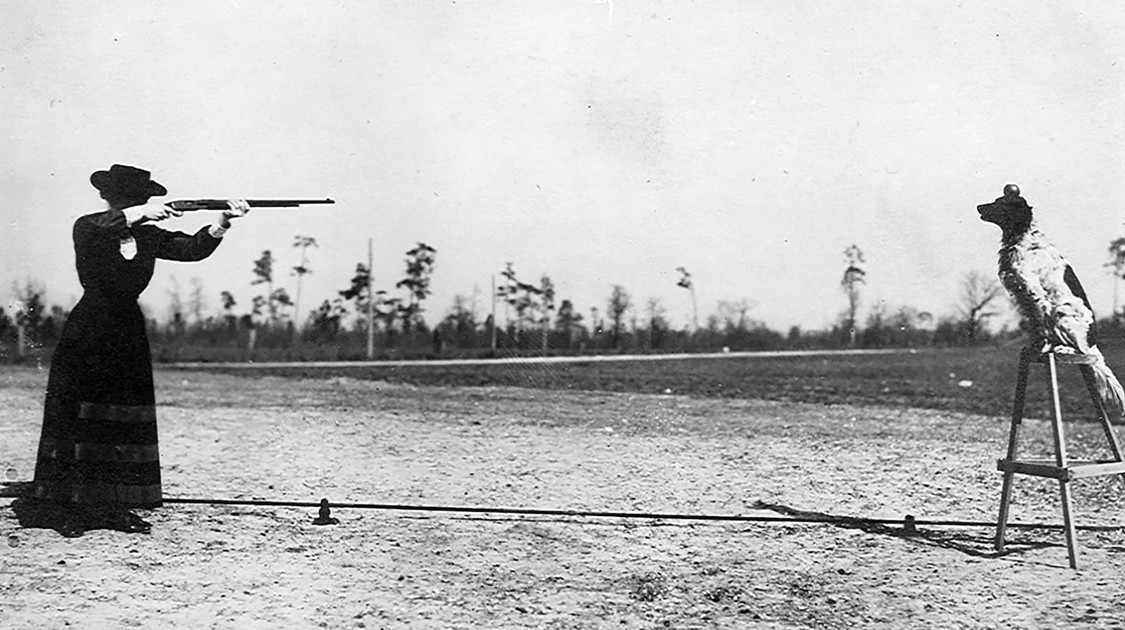 Annie Oakley takes aim at an apple sitting on top of her dogs' head. The English setter, named "Dave," grew so accustomed to the sound of gun fire while hunting with Oakley and her husband Frank Butler he became part of their show. PHOTO COURTESY OF THE NATIONAL ANNIE OAKLEY CENTER AT THE GARST MUSEUM