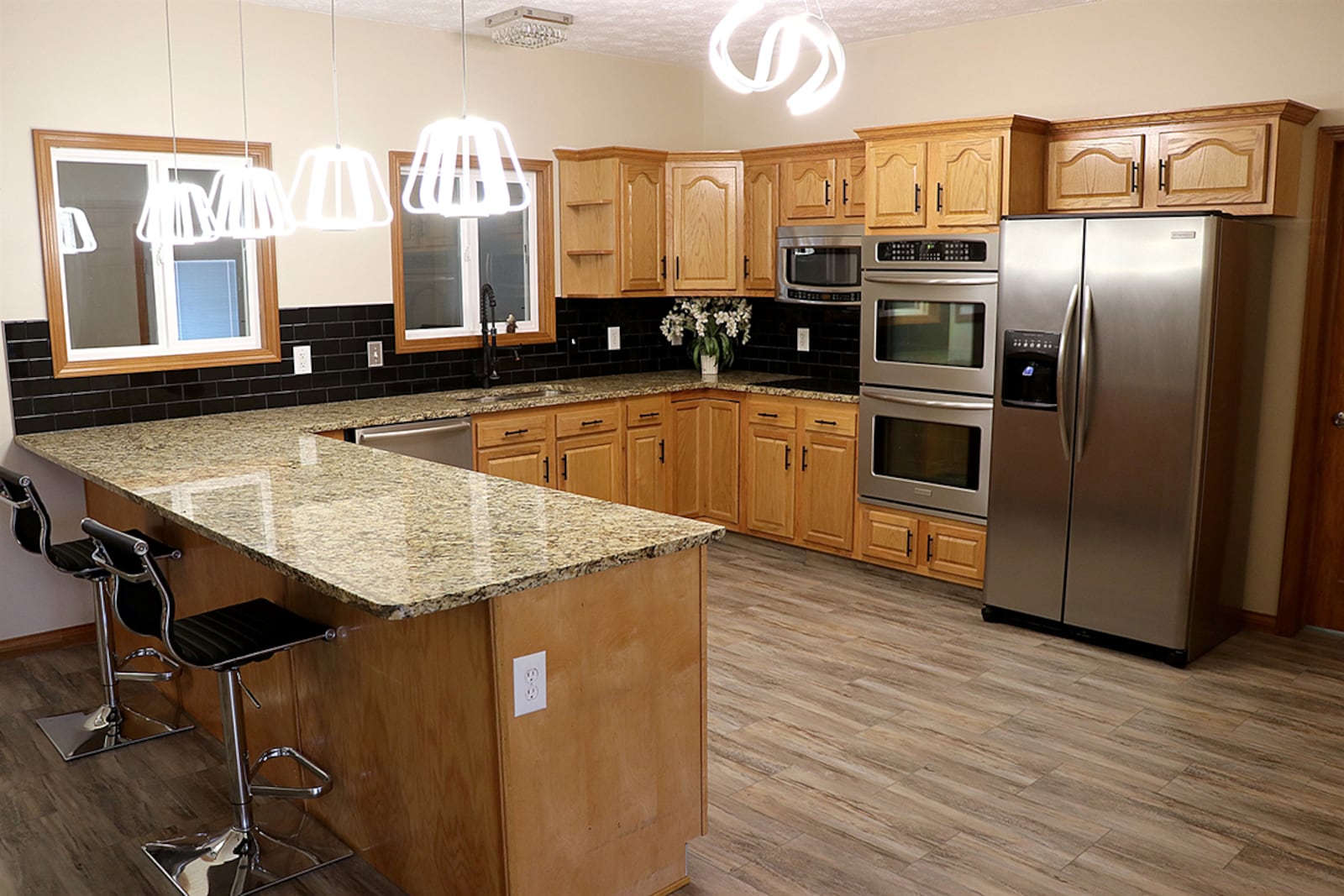 A kitchen has oak cabinetry with a sink within the peninsula countertop. Beveled countertops complement the oak cabinetry, which fills two walls and surrounds stainless-steel appliances. CONTRIBUTED PHOTO BY KATHY TYLER