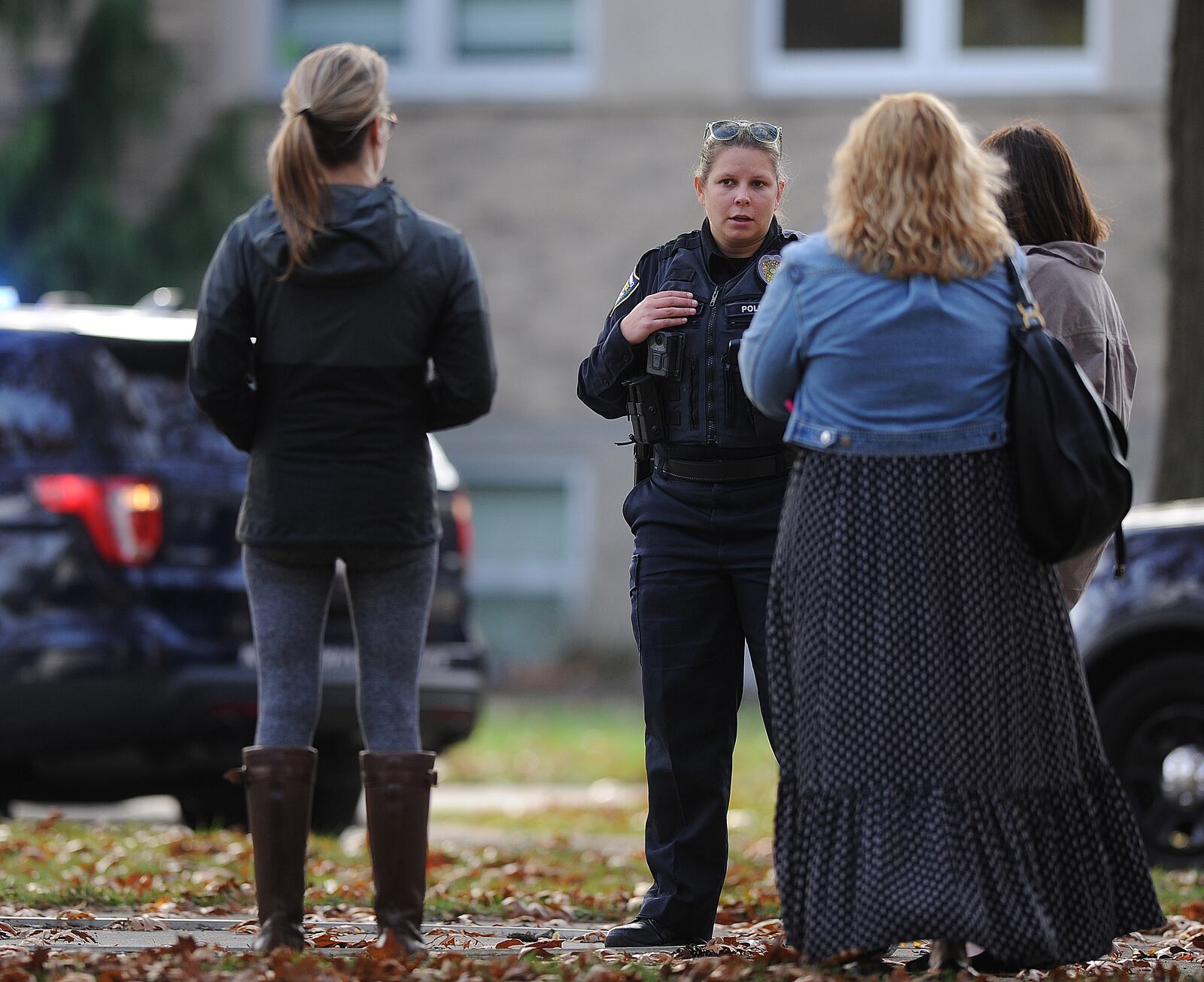 A member of the Kettering Police Department talks with Alter High School parents Wednesday, Nov. 8, 2023. Kettering police received a report of gunfire outside Archbishop Alter High School that was later determined to be false. MARSHALL GORBY\STAFF