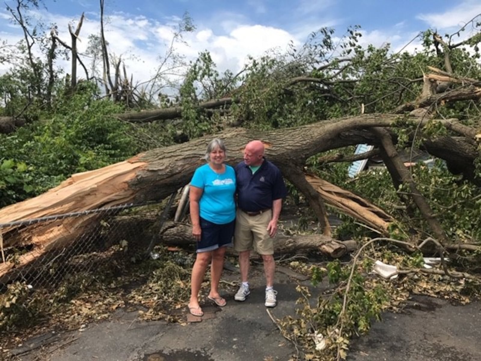 Rich Munn and Patti Stearns stand in front of flattened garage covered by fallen trees. Photo by Tom Archdeacon