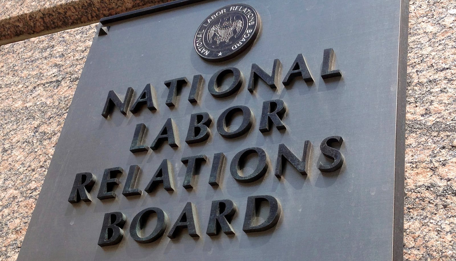 FILE - The sign for the National Labor Relations Board is seen on the building that houses their headquarters in downtown Washington, July 17, 2013. (AP Photo/Jon Elswick, file)