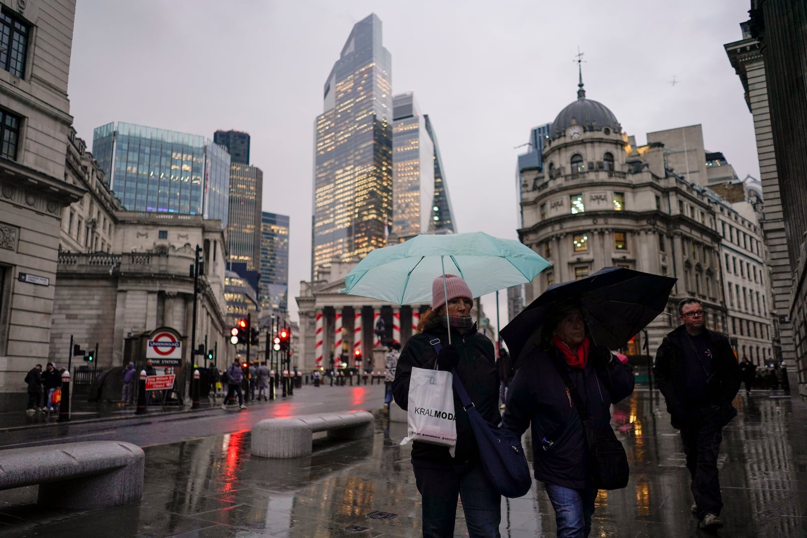 People hold umbrellas as they walk in front of the Bank of England, at the start of a week that is set to see the temperatures drop, in London, Monday, Nov. 18, 2024. (AP Photo/Alberto Pezzali)