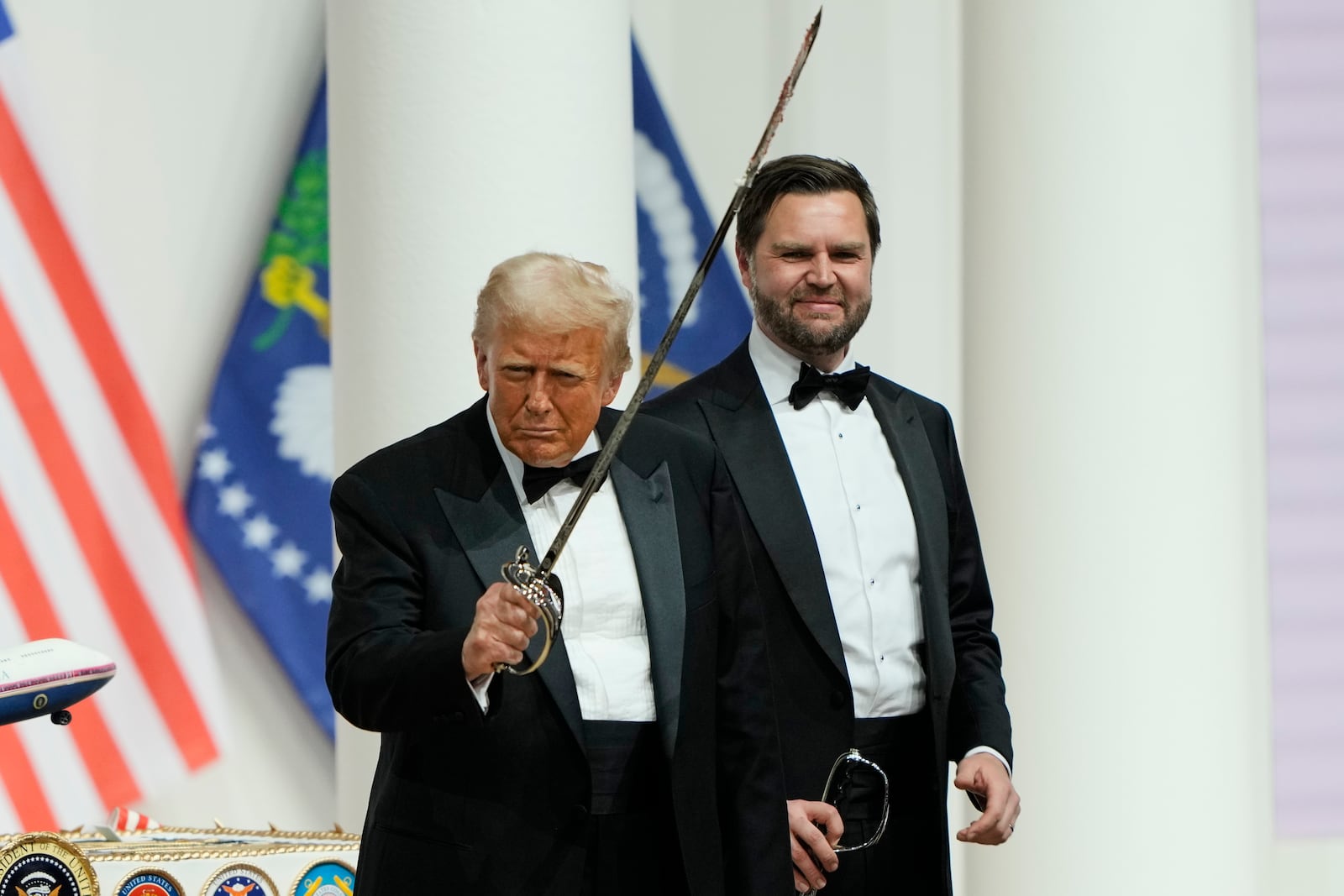 President Donald Trump, left, holds a sabre after using it to cut a cake, as Vice President JD Vance looks on, at the Commander in Chief Ball, part of the 60th Presidential Inauguration, Monday, Jan. 20, 2025, in Washington. (AP Photo/Ben Curtis)