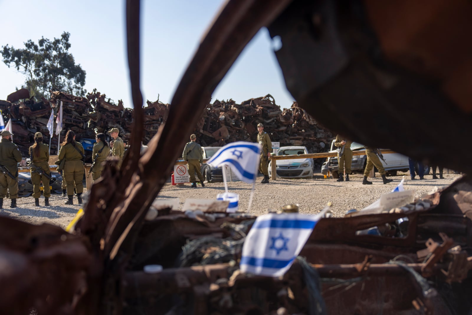 Israeli soldiers look at charred vehicles burned in the Oct. 7 , 2023, cross-border attacks by Hamas militants outside the town of Netivot, southern Israel, Monday, Jan. 13, 2025. (AP Photo/Ariel Schalit)