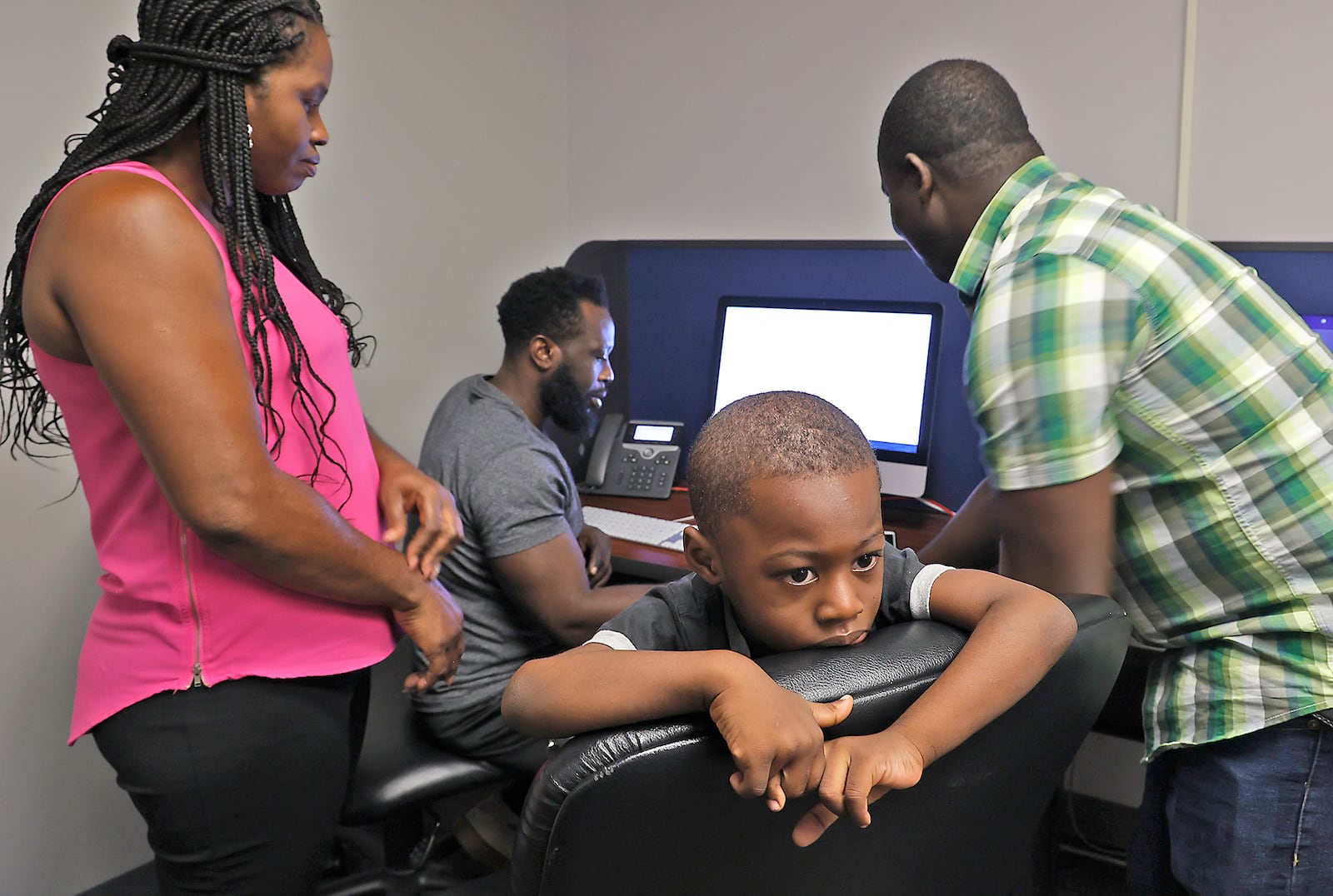 Kepler Jean Baptiste looks around the room as Malachi Thebaud, a bilingual assistant, right, helps his father, Jean Paul Jean Baptiste, and mother, Eveline Port Louis, register him for school in the Springfield City School District Tuesday, August 1, 2023. BILL LACKEY/STAFF