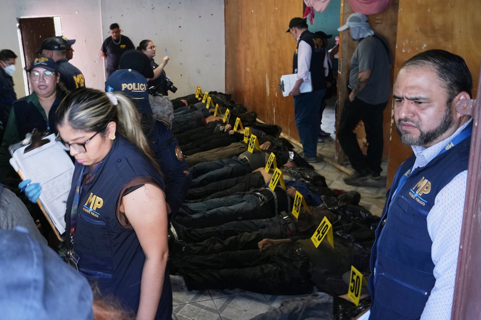 The bodies of passengers who died in a bus crash are lined up on the floor at a makeshift morgue near the site of the accident on the outskirts of Guatemala City, Monday, Feb. 10, 2025. (AP Photo/Moises Castillo)