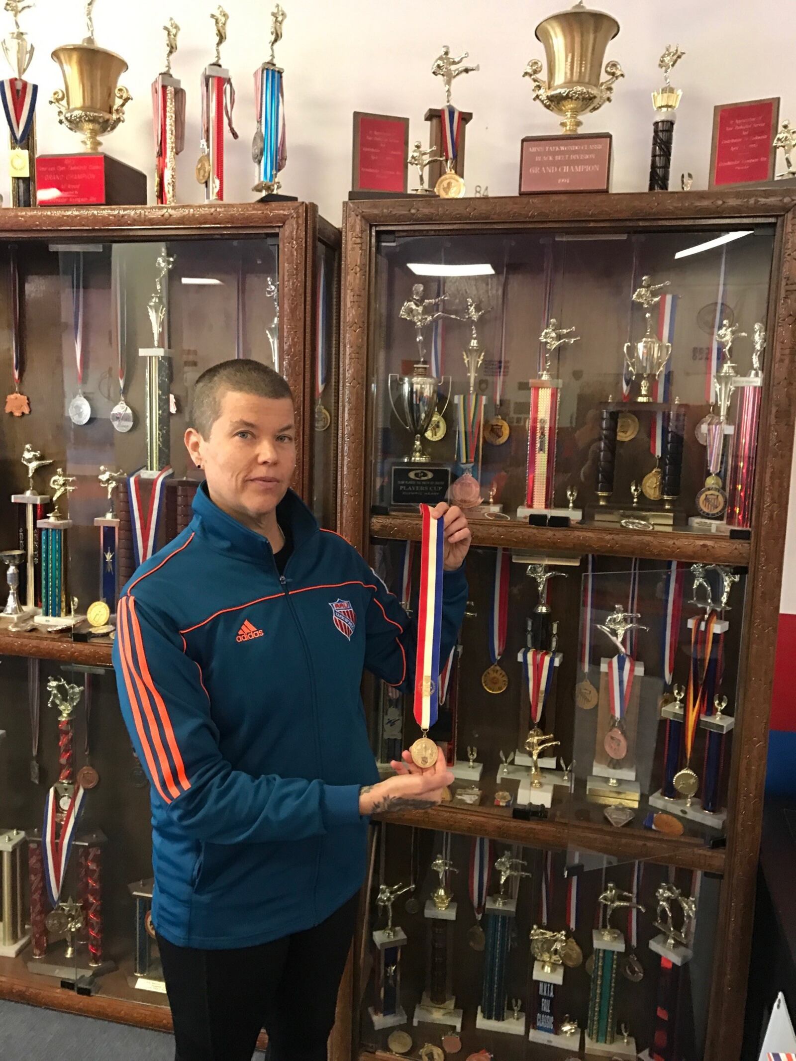 Christina Bayley holds one of the first medals she won in a long and successful career as a Taekwondo champion. Her dad built the trophy cases behind her and today – displayed at her school on Stroop Road, Total Taekwondo and Fitness – they are overflowing with the trophies , plaques and medals she won. Tom Archdeacon/STAFF