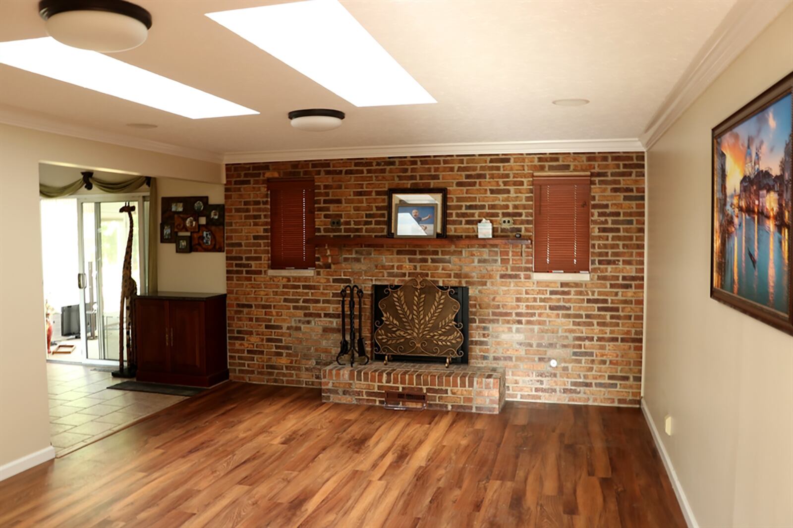 The family room has a brick, gas fireplace. The full brick wall has windows built-in that flank the wood-beam mantel, and there is a raised, brick hearth. CONTRIBUTED PHOTO BY KATHY TYLER