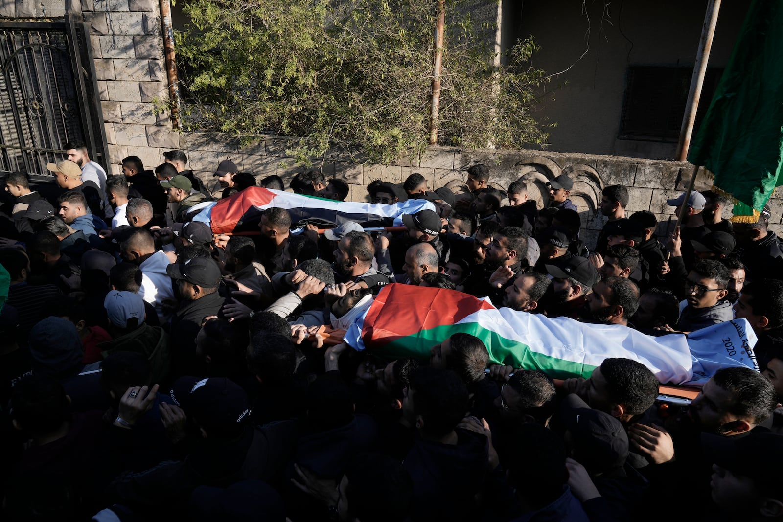 Mourners carry the bodies wrapped with the Palestinian flag, of Akram Abu Arrah and Mohammad Ghannam, both killed in an airstrike Israel said targeted a militant cell, during their funeral in the West Bank village of Al-Aqaba, Tuesday Dec. 3, 2024. (AP Photo/Majdi Muhammad)