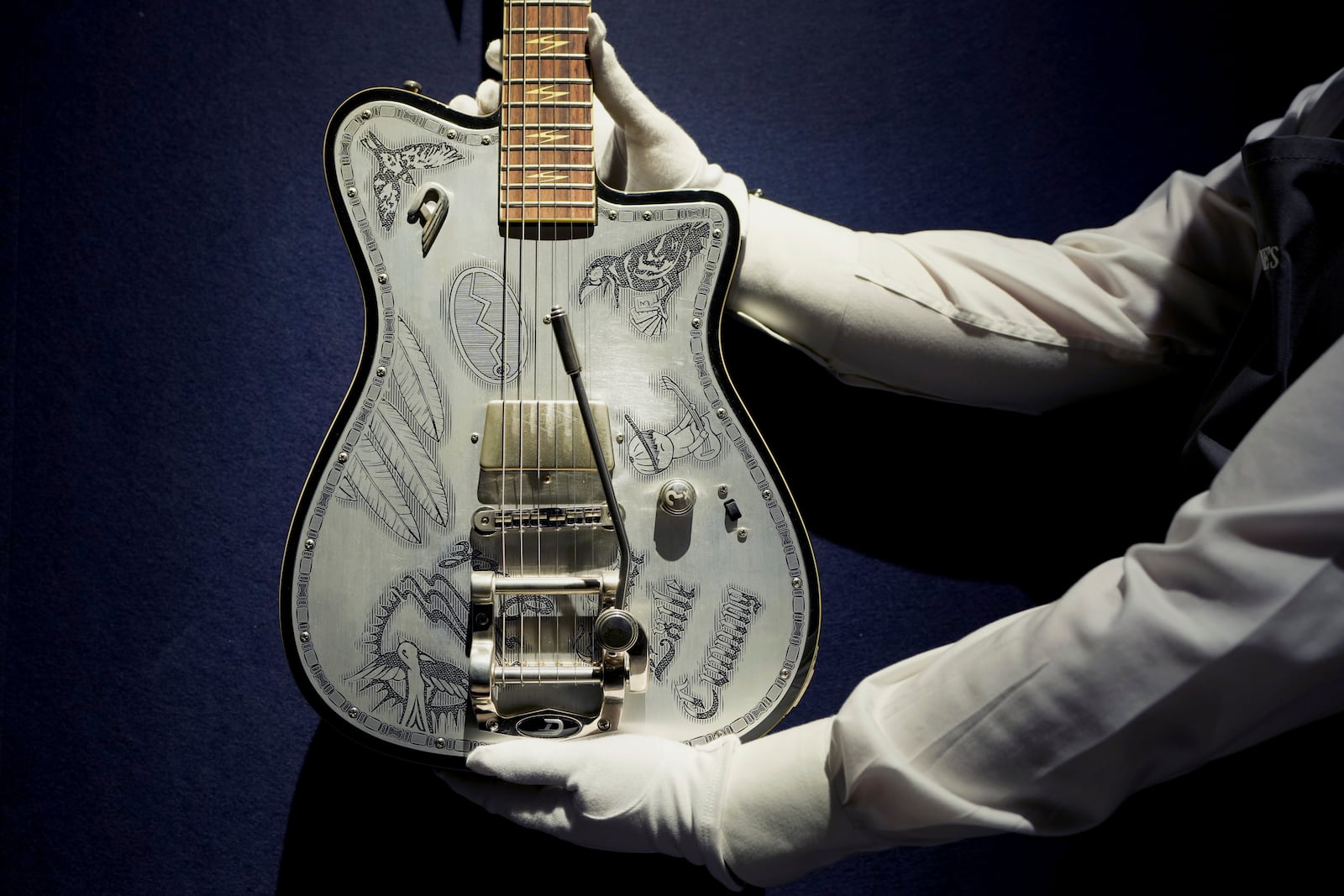 An art handler displays a Duesenburg, Hanover, Germany, 2019, a semi solid-body electric guitar, artist series Johnny Depp signature, custom built for Jeff Beck, in London, Tuesday, Jan. 14, 2025, ahead of the pre-sale exhibition at Christie's auction rooms. (AP Photo/Kirsty Wigglesworth)