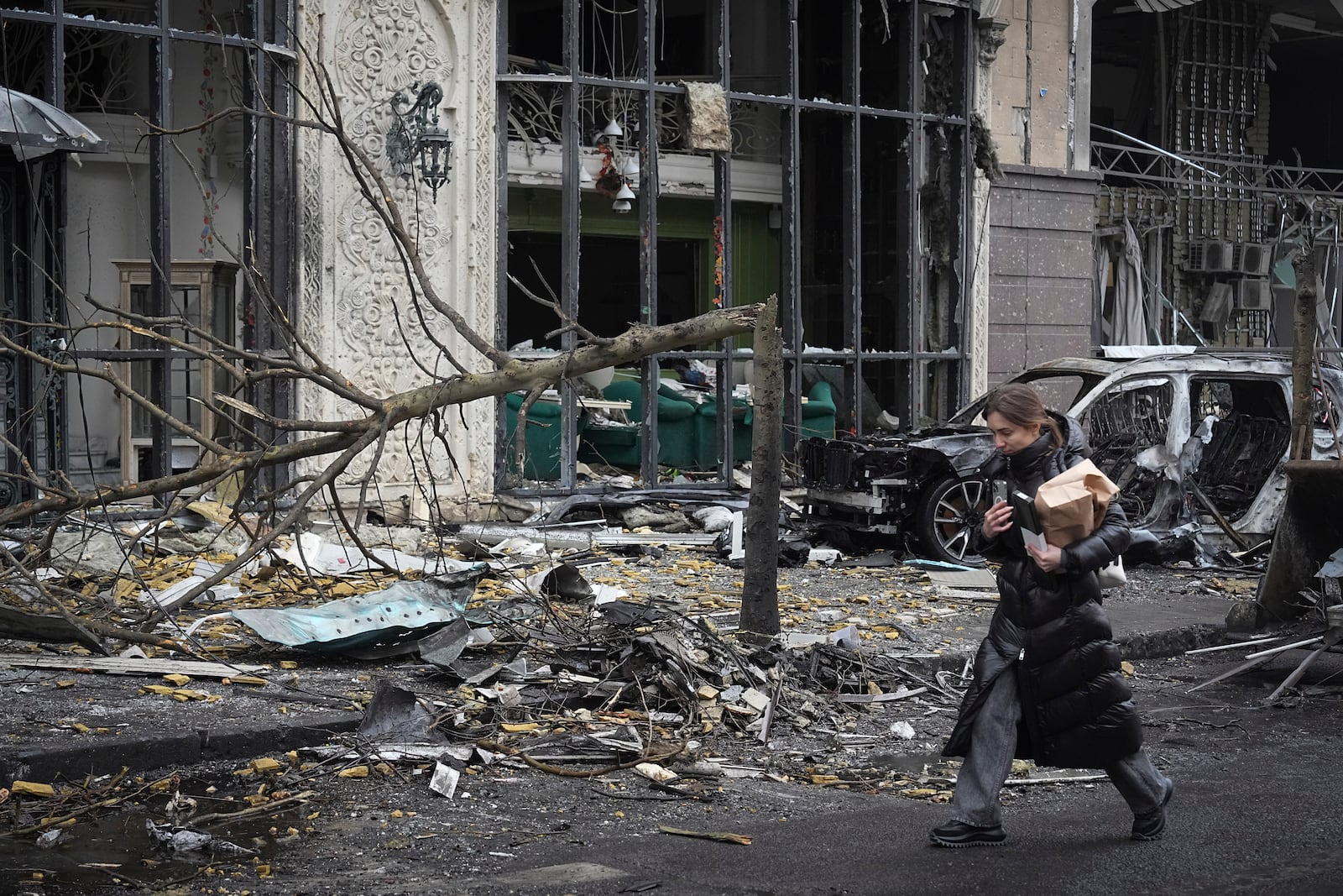 A woman paces past buildings destroyed by recent Russian attacks in Kyiv, Ukraine, Friday, Dec. 20, 2024. (AP Photo/Efrem Lukatsky)