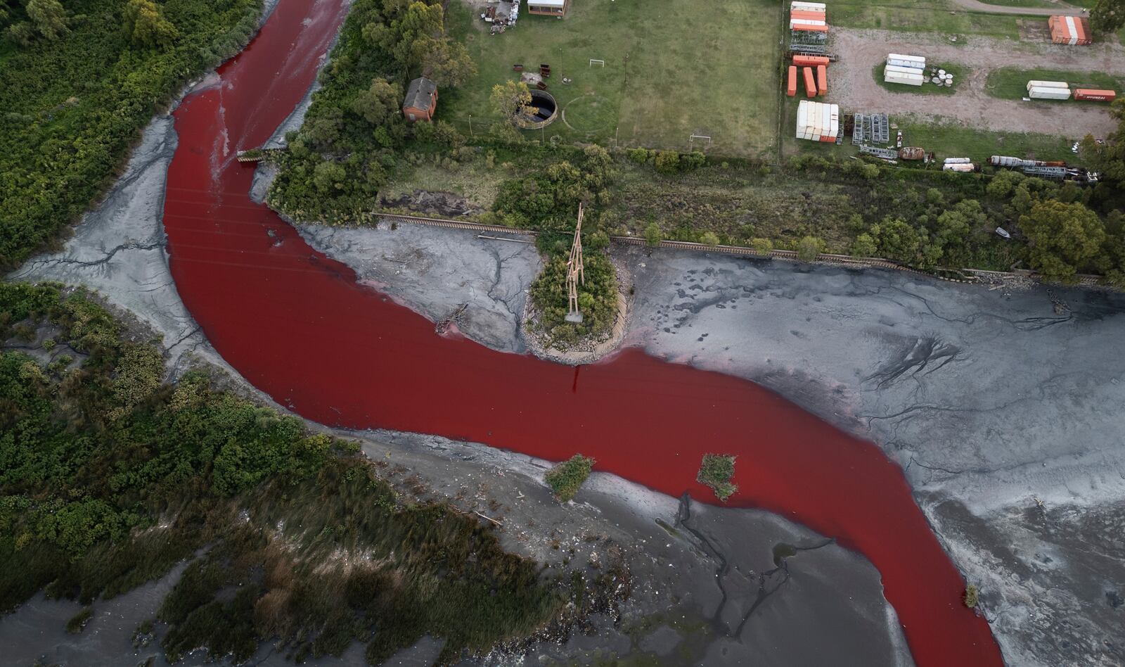 An aerial view of the "Sarandi" stream dyed red due to unknown contaminants allege residents, in an industrial neighborhood on the outskirts of Buenos Aires, Argentina, Thursday, Feb. 6, 2025. (AP Photo/Rodrigo Abd)