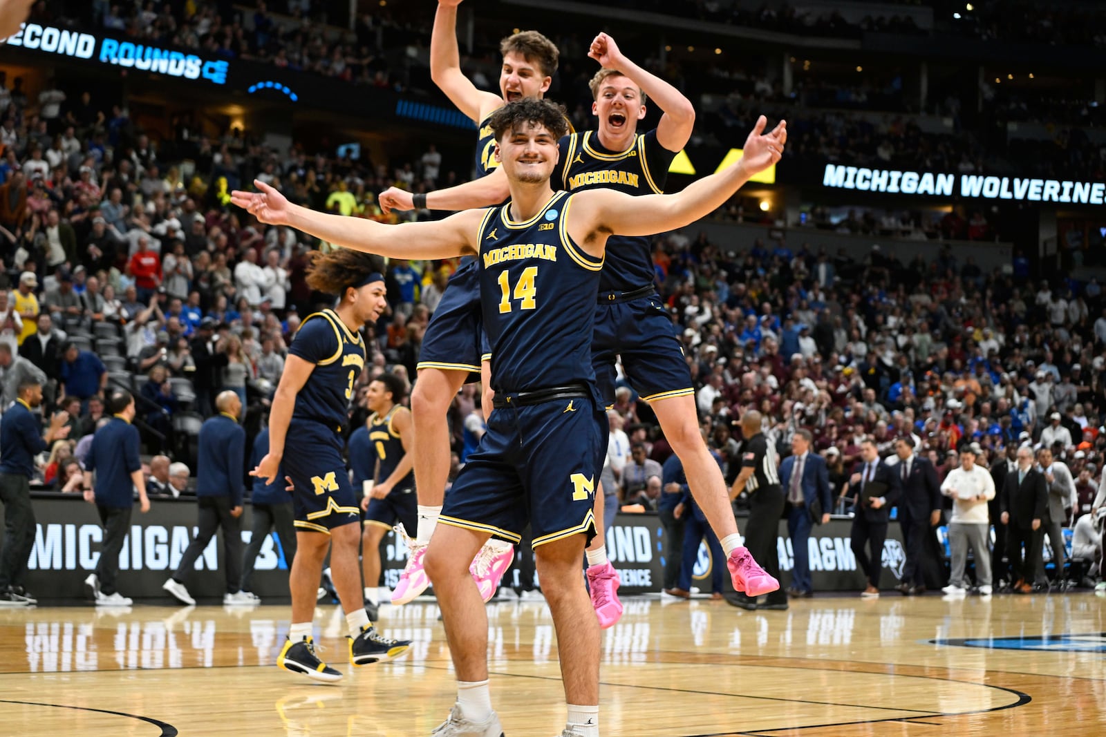 Michigan guard Ian Burns, front, joins forward Will Tschetter and guard Charlie May in celebrating after defeating Texas A&M in the second round of the NCAA college basketball tournament Saturday, March 22, 2025, in Denver. (AP Photo/John Leyba)