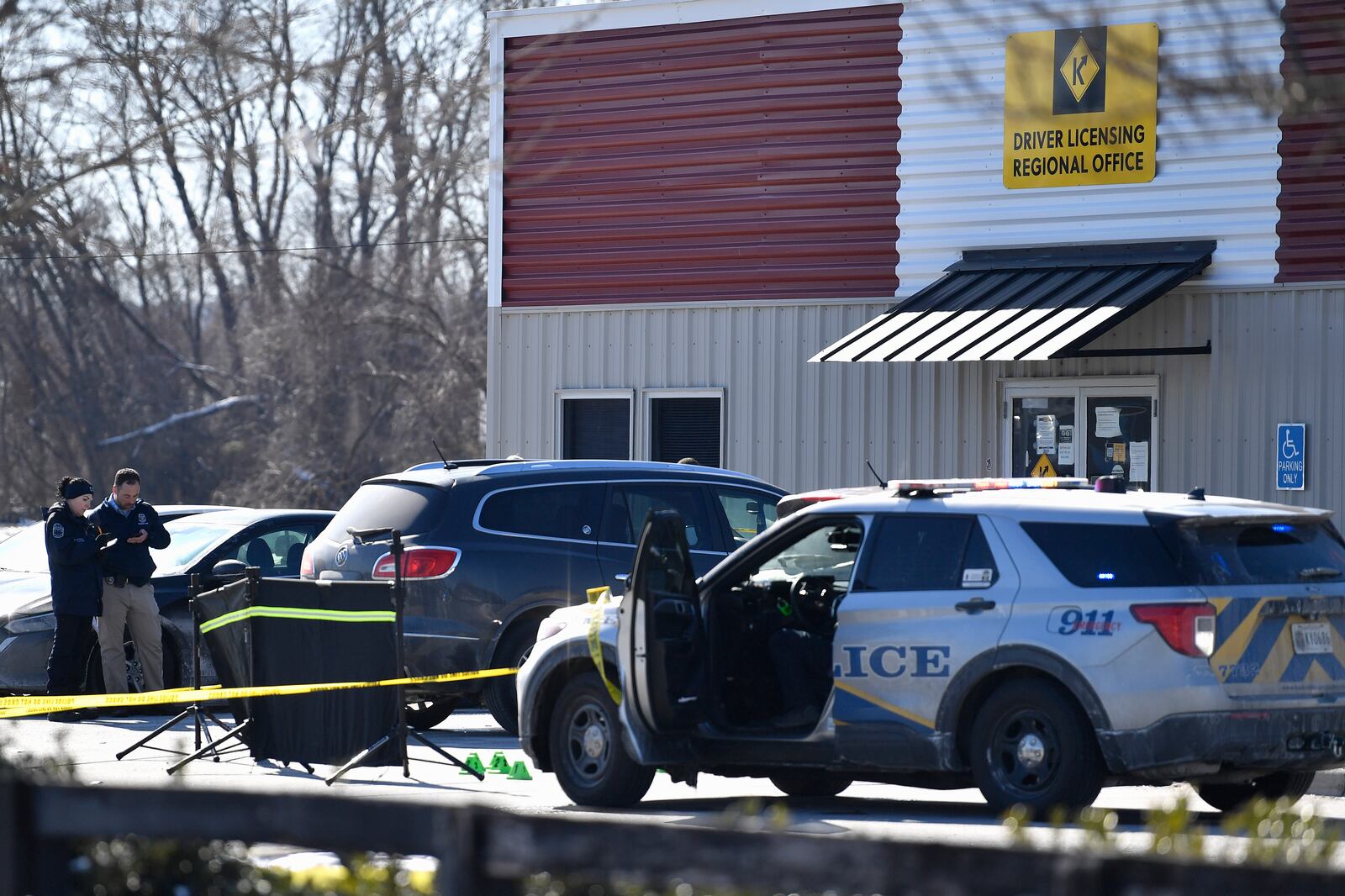 Detectives with the Louisville Metro Crime Scene unit examines a scene of a deadly shooting outside a motor vehicle office in Louisville, Ky., Friday, Feb. 21, 2025. (AP Photo/Timothy D. Easley)