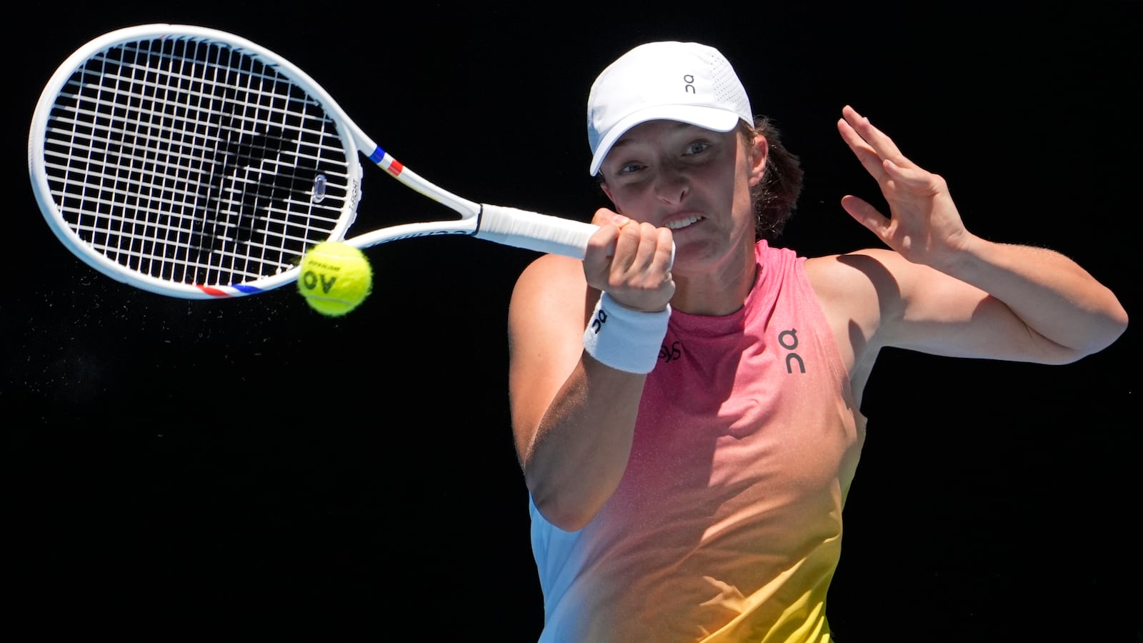 Iga Swiatek of Poland plays a forehand return to Emma Raducanu of Britain during their third round match at the Australian Open tennis championship in Melbourne, Australia, Saturday, Jan. 18, 2025. (AP Photo/Asanka Brendon Ratnayake)