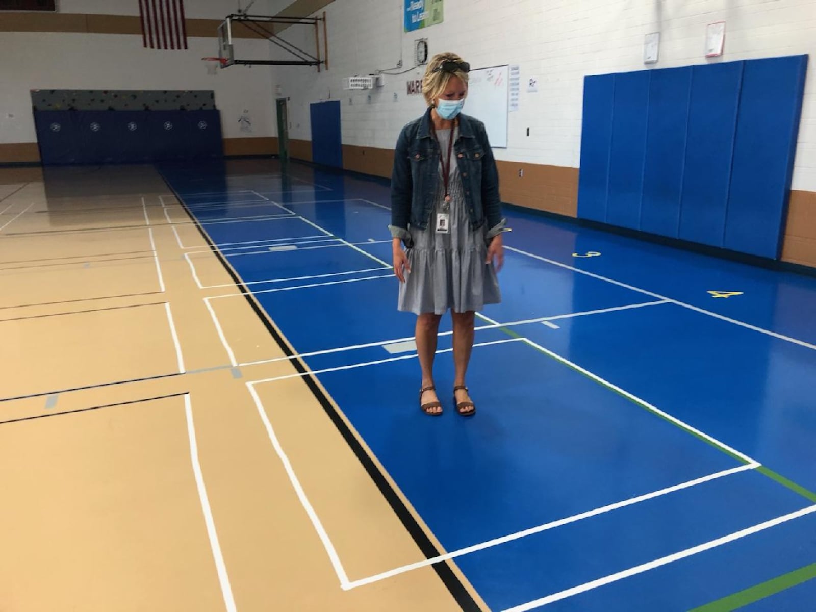 Principal Sheri McHenry stands in the middle of a square drawn on a gym floor to demonstrate how students will be socially distance during class.