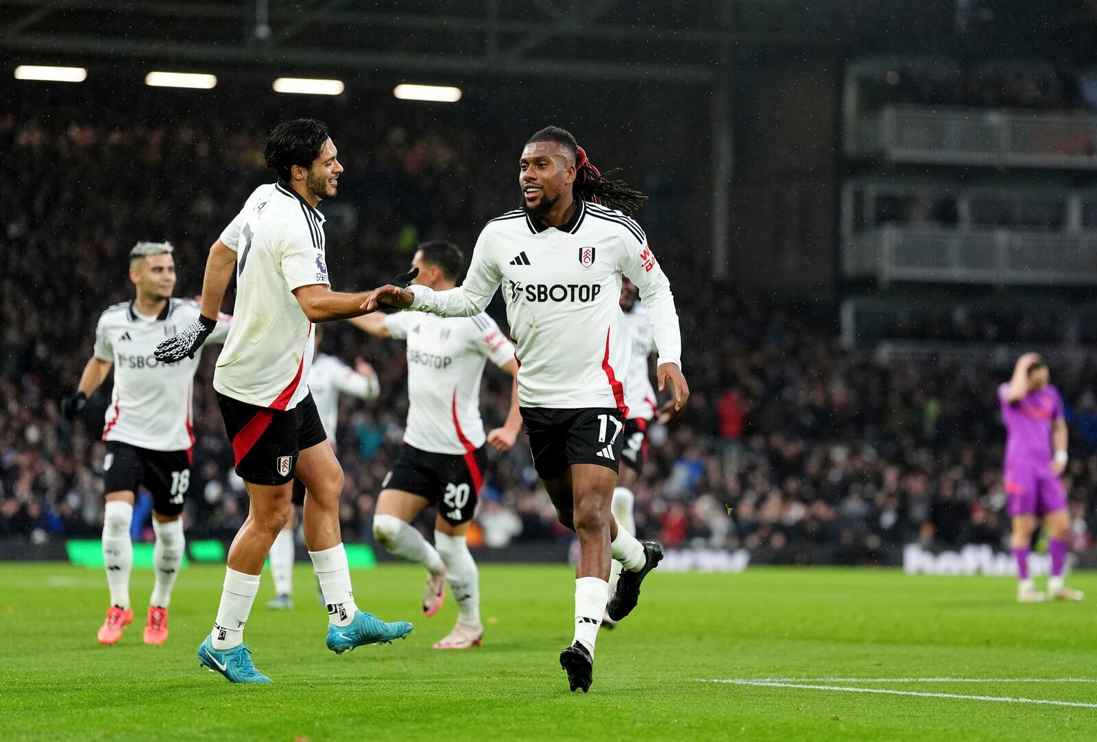 Fulham's Alex Iwobi, right, celebrates after scoring the opening goal during the English Premier League match between Fulham and Wolverhampton Wanderers at Craven Cottage stadium in London, Saturday, Nov. 23, 2024. (Zac Goodwin/PA via AP)