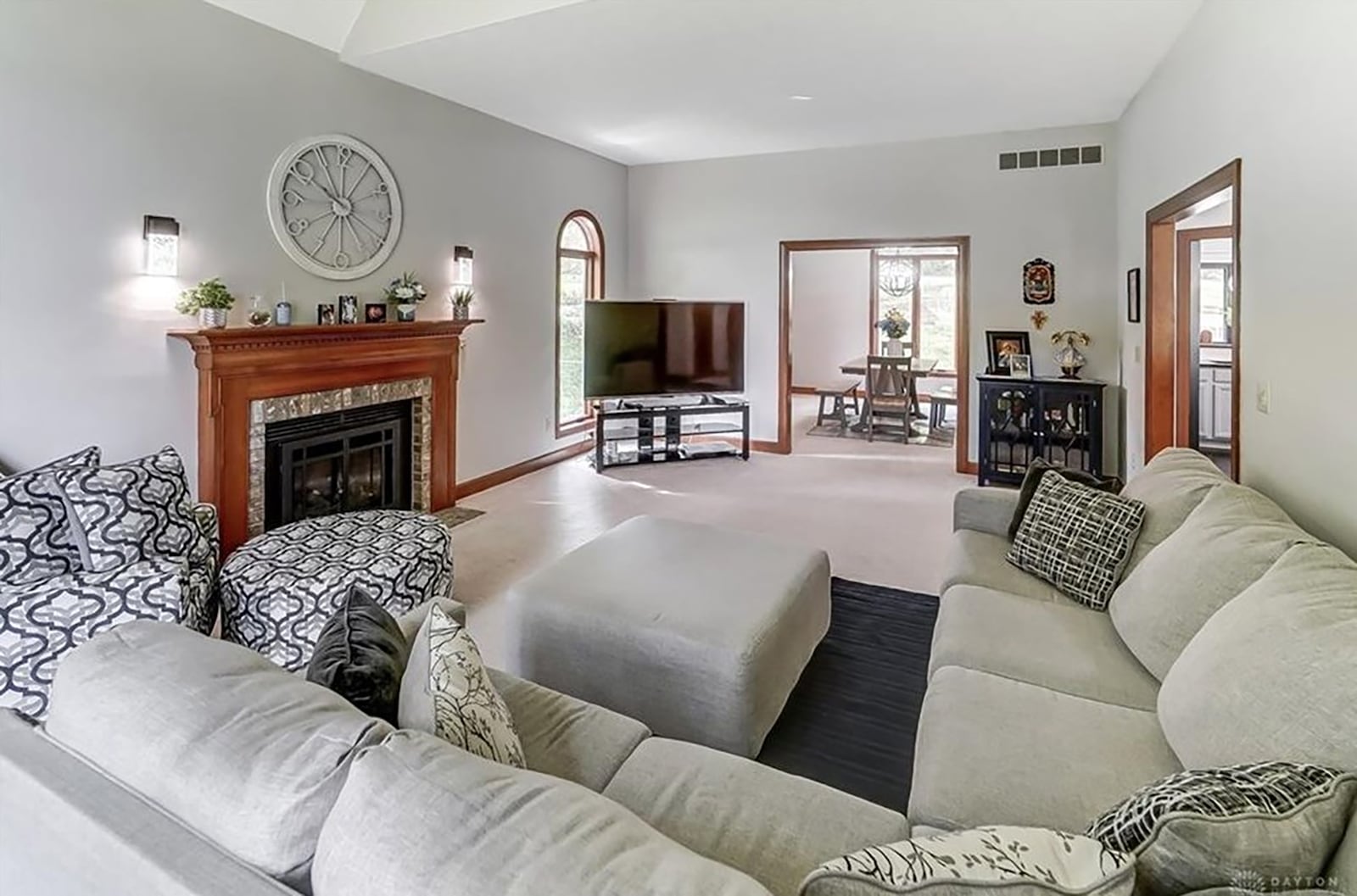 The great room is vaulted and has a gas fireplace, neutral carpeting and recessed lighting as well as a ceiling fan.