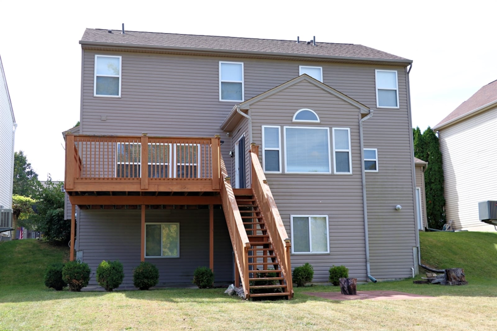 A large balcony wooden deck covers the concrete backyard patio.