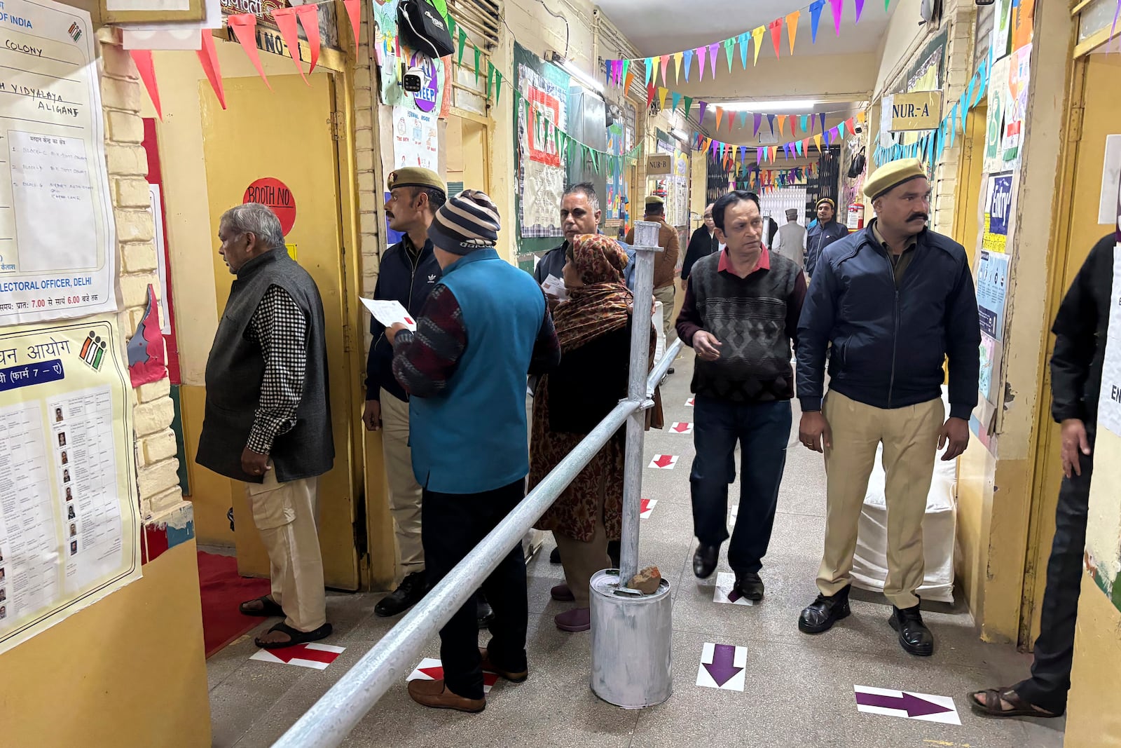 People stand in a queue to cast their votes for the capital’s state legislature election at a polling booth in New Delhi, India, Wednesday, Feb. 5, 2025. (AP Photo/Shonal Ganguly)